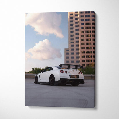 White Nissan GTR R35 parked under blue sky, modern building backdrop, vertical canvas wall art.