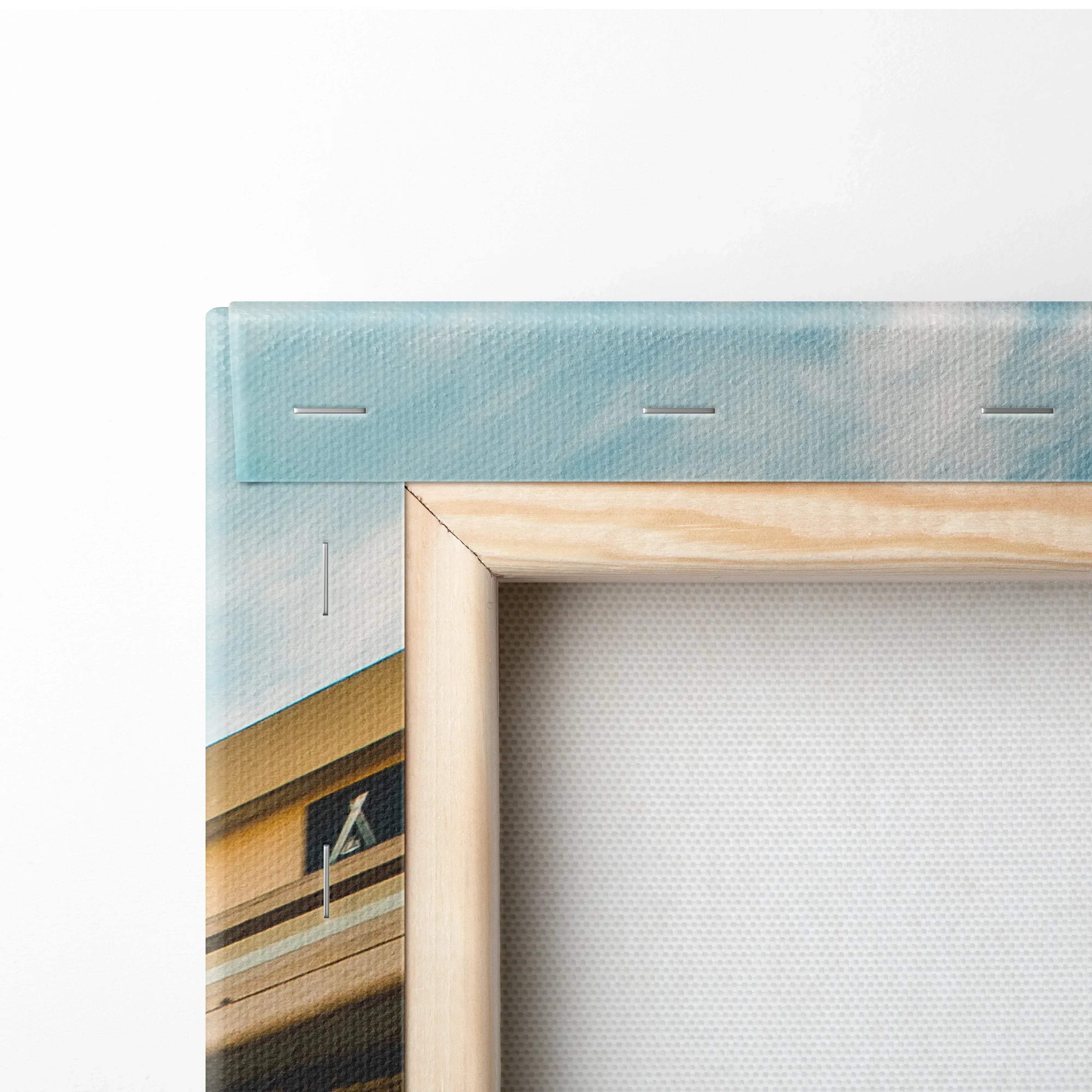 Corner view of stretched canvas art with wooden frame and architectural print in soft blue and beige tones.