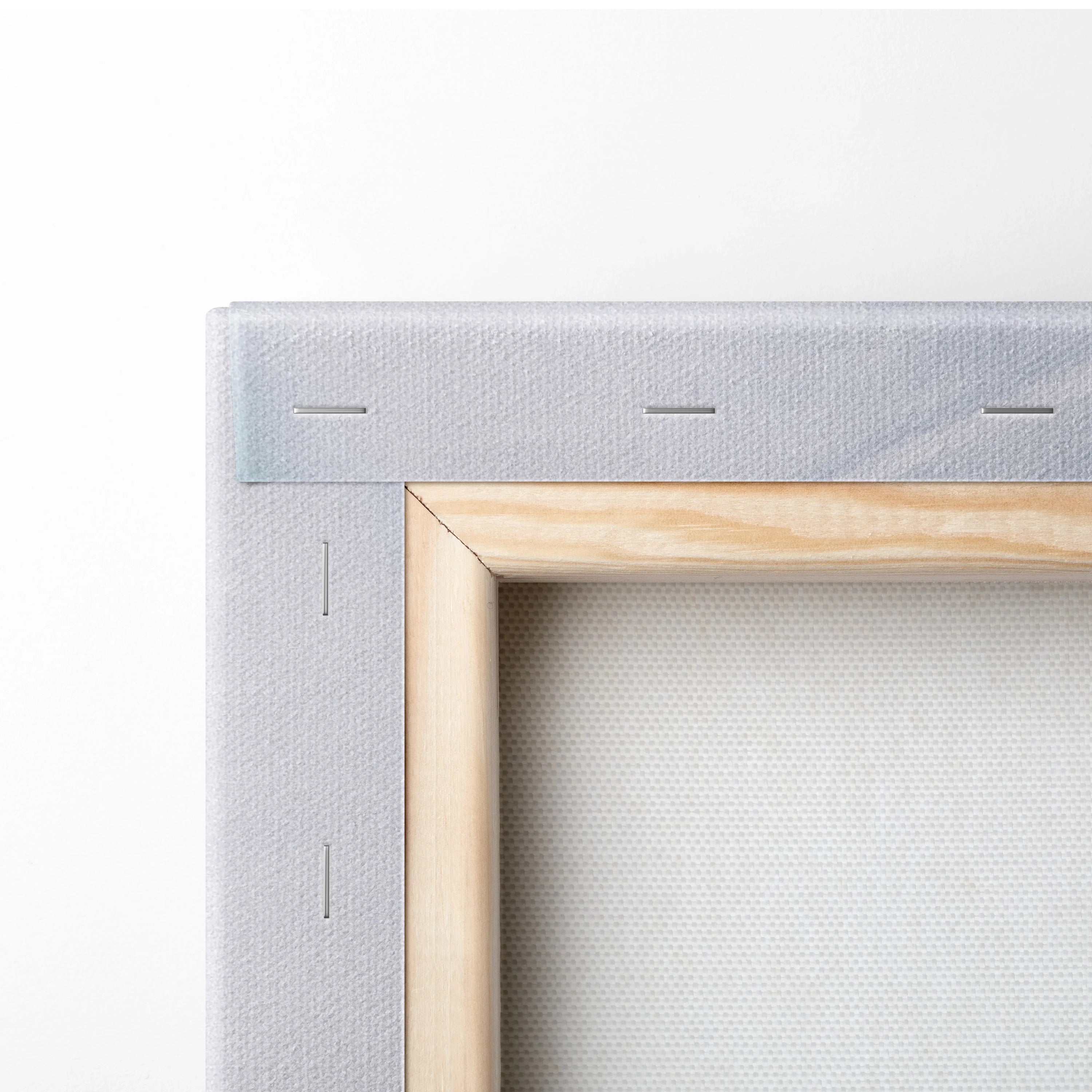 Close-up of natural wood frame and gray canvas stretch with visible staples on wall art canvas edges.