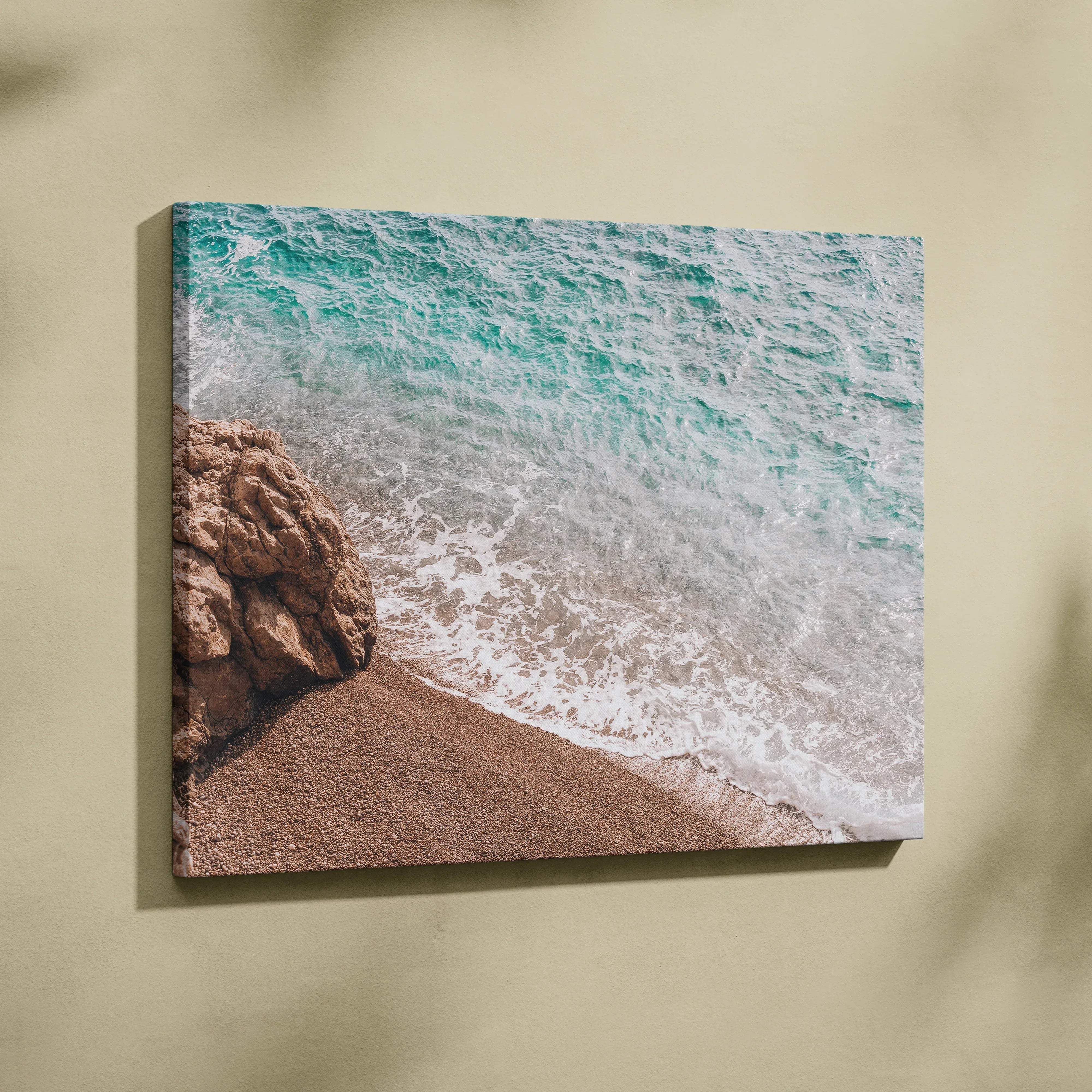 Vibrant turquoise ocean wave crashing on sandy beach with rocks, canvas wall art