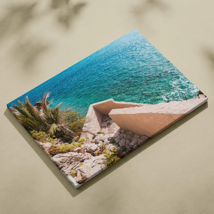 Canvas wall art featuring bright blue ocean waves meeting rocky shore with modern beige architectural structure.