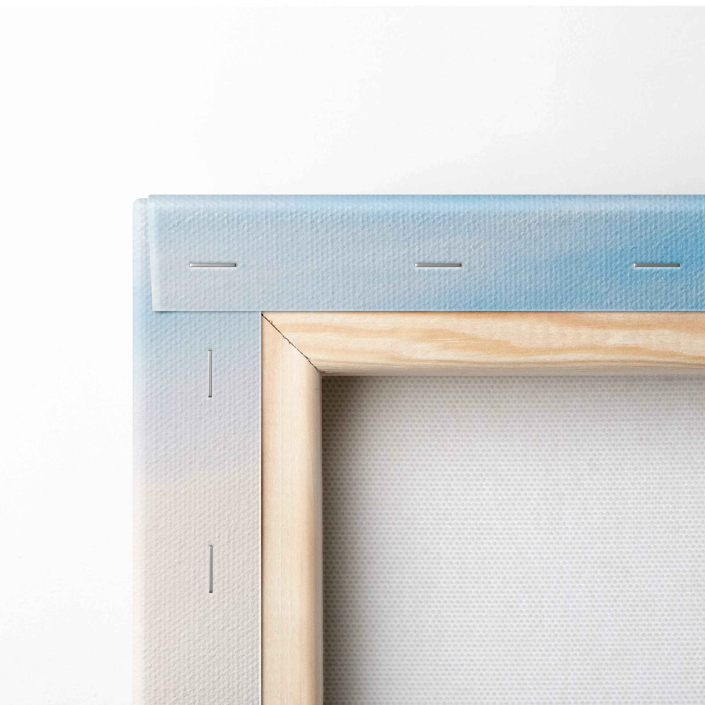 Close-up of stretched canvas fabric secured with staples on a natural wood frame corner with light blue edges.