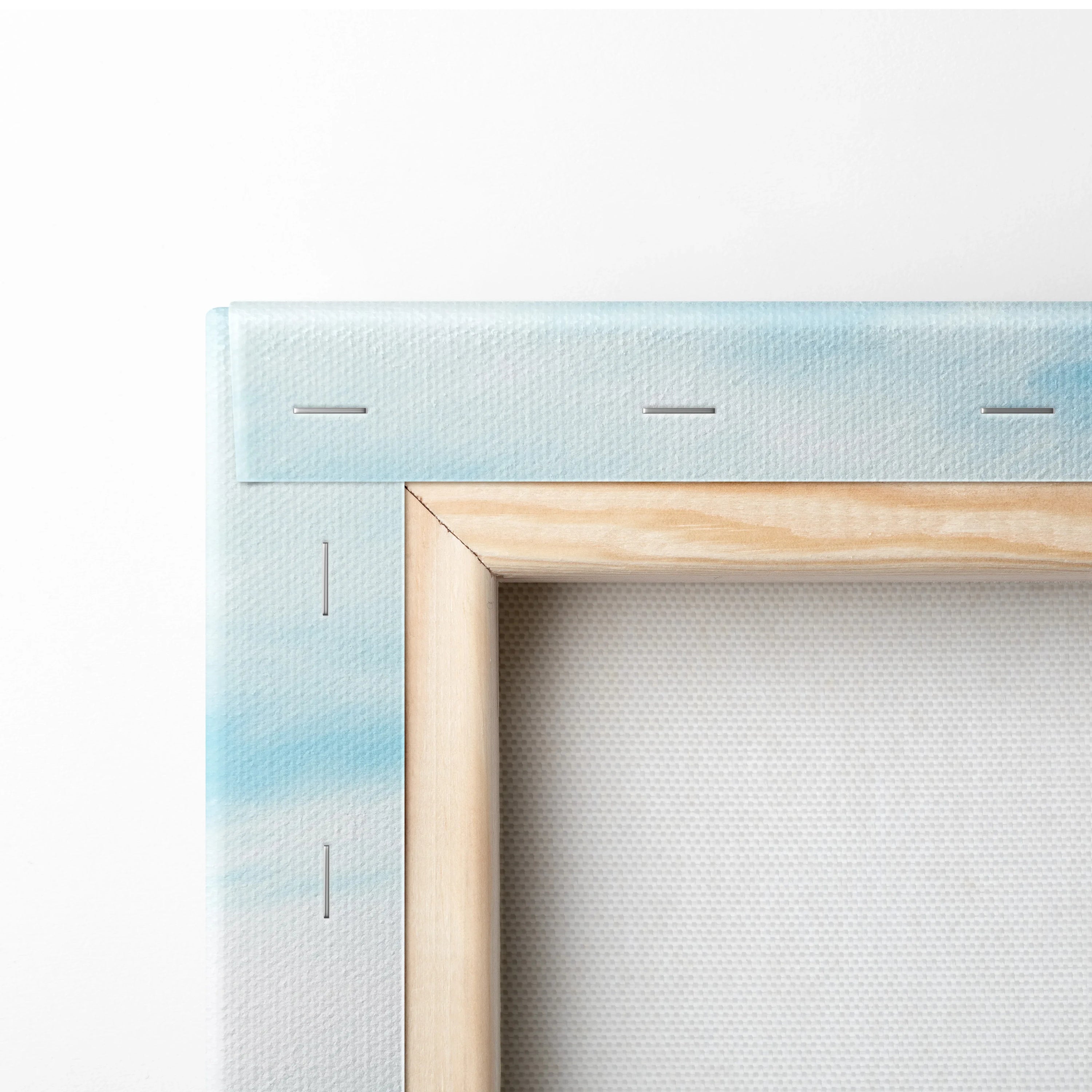 Close-up of stretched canvas art with light blue and white tones on wooden frame corner.