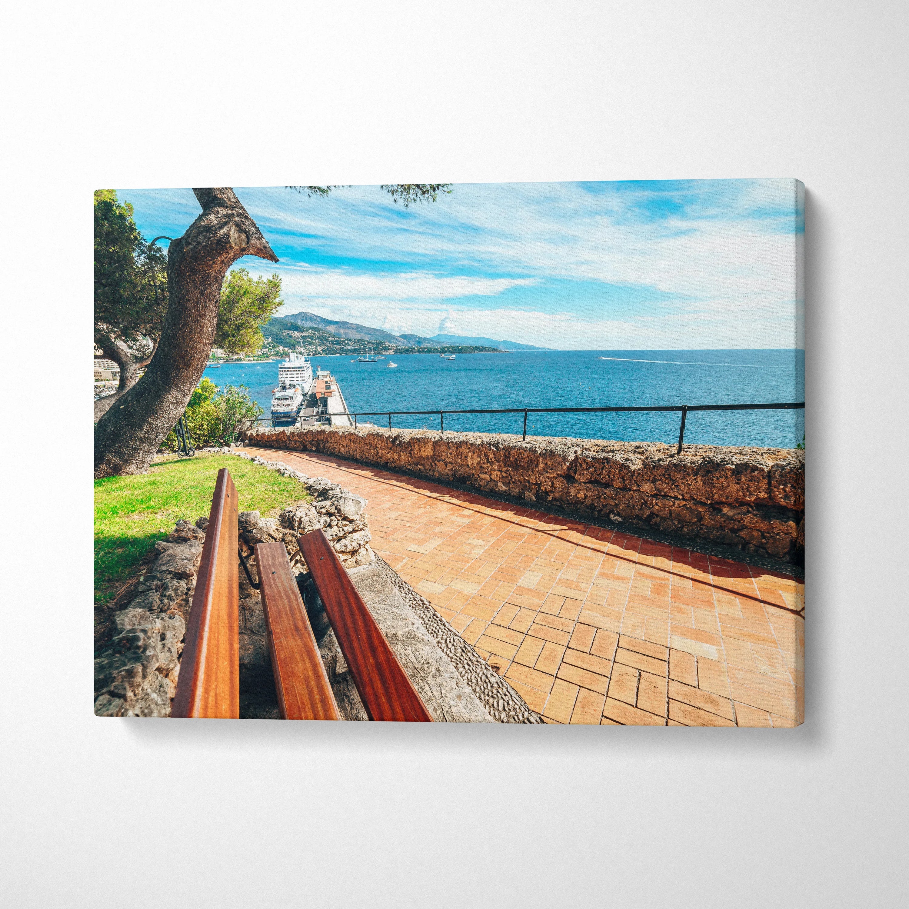 Beachside walkway with wooden benches along the stone wall under a blue sky canvas wall art.