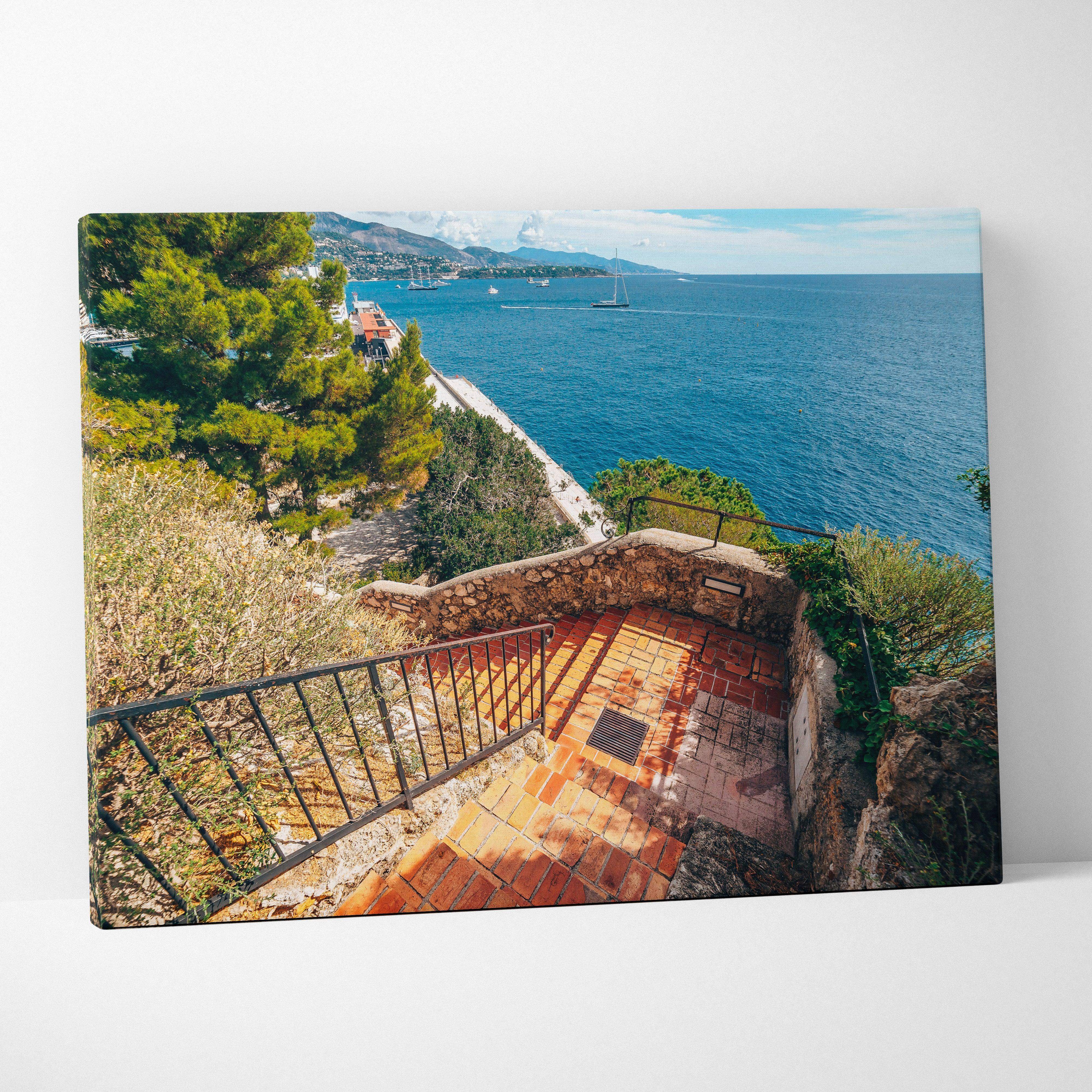 A rectangular canvas wall art featuring terracotta stairs leading to turquoise sea with sailboats and greenery