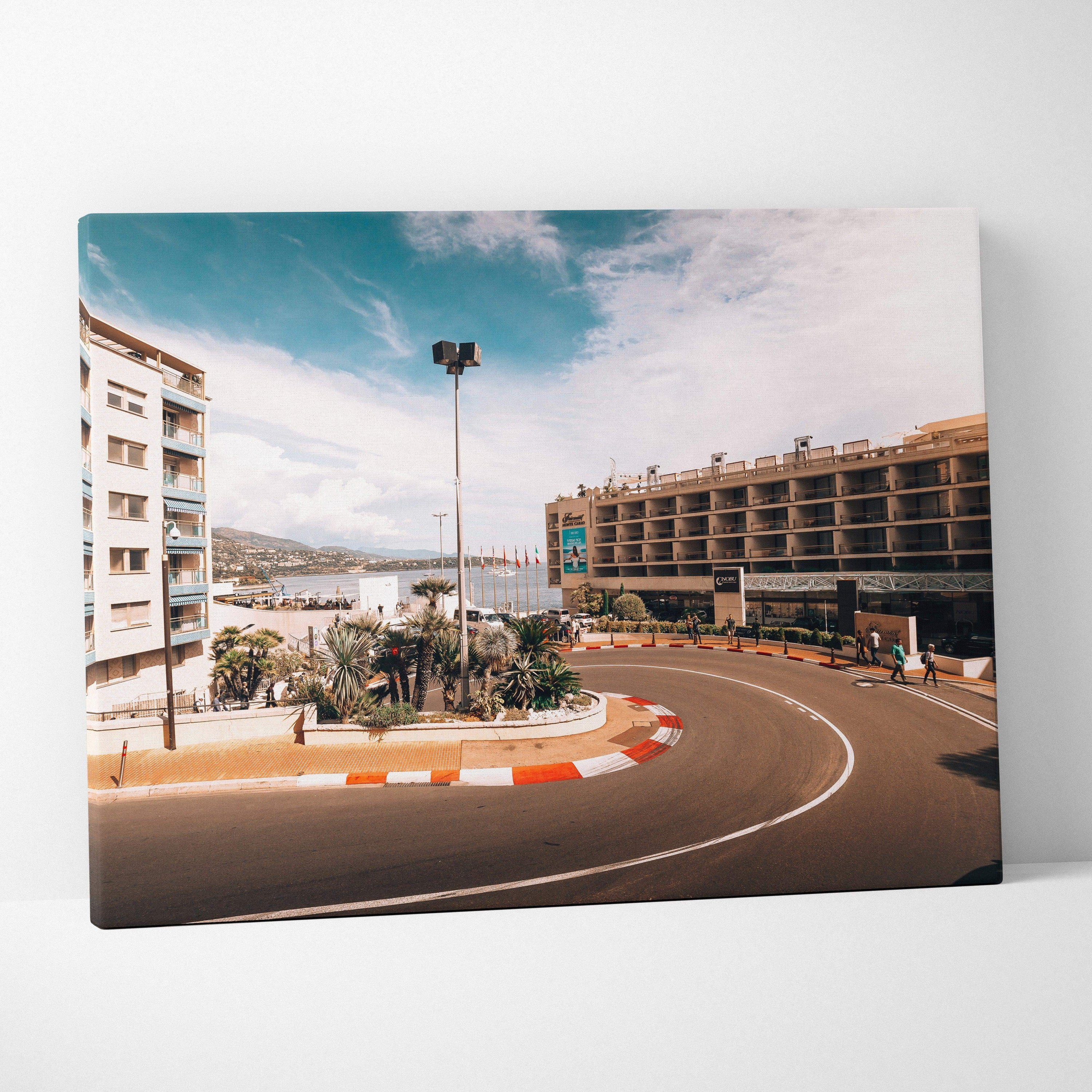 Canvas wall art featuring a curved F1 track corner with surrounding buildings under a blue sky.