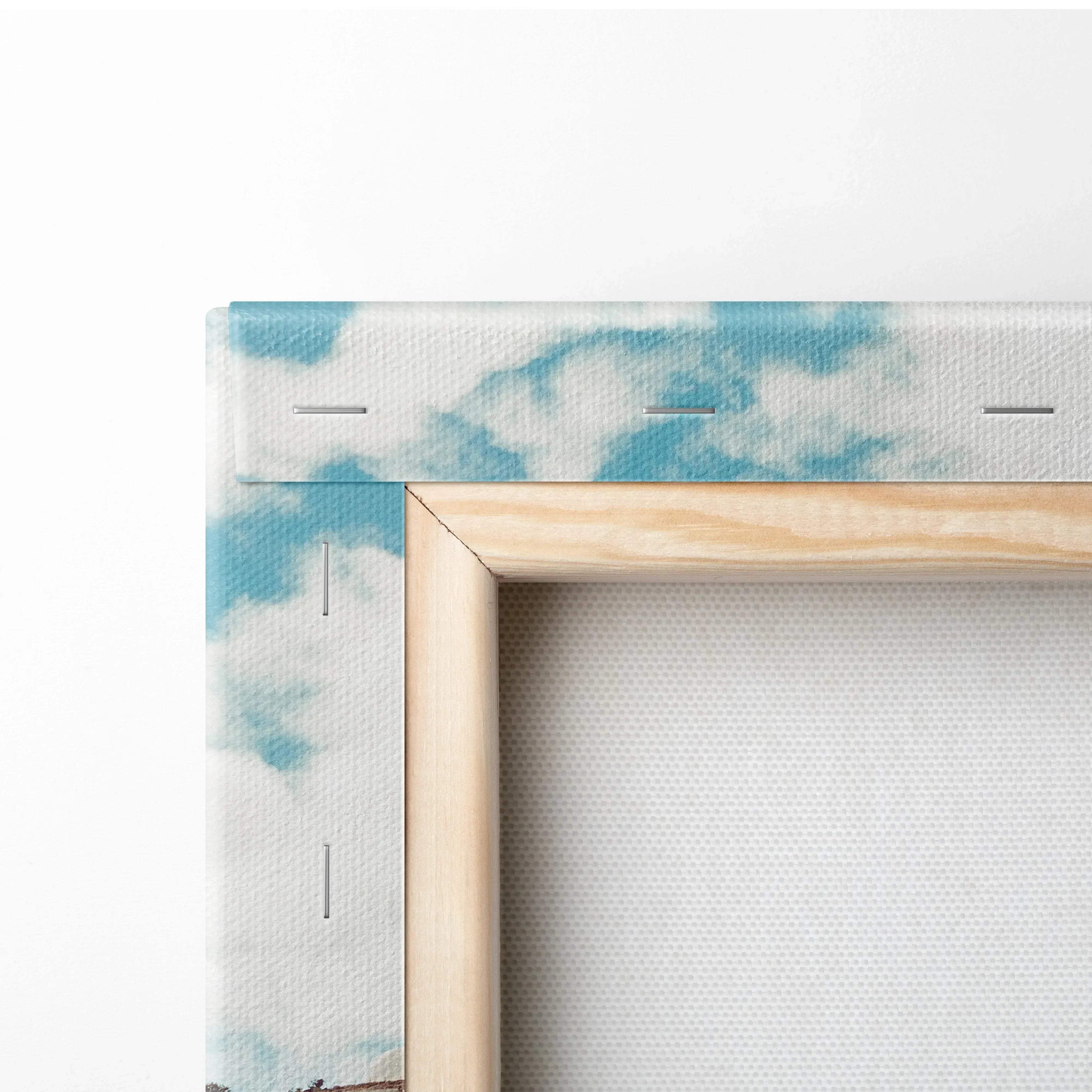 Close-up of corner of stretched canvas wall art with blue and white cloud design and natural wood frame.