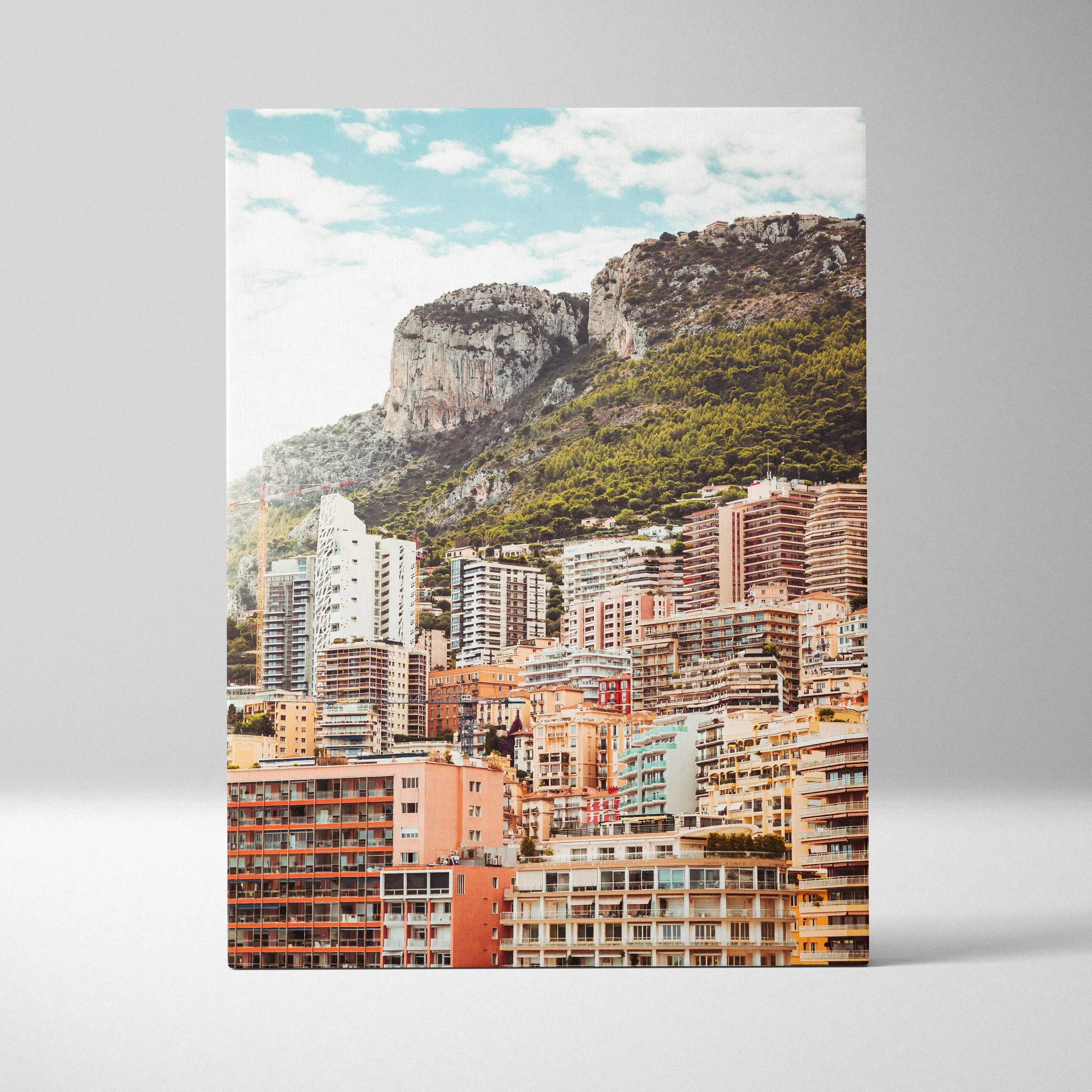 Vertical canvas wall art featuring colorful cityscape buildings with green mountains and blue sky backdrop.