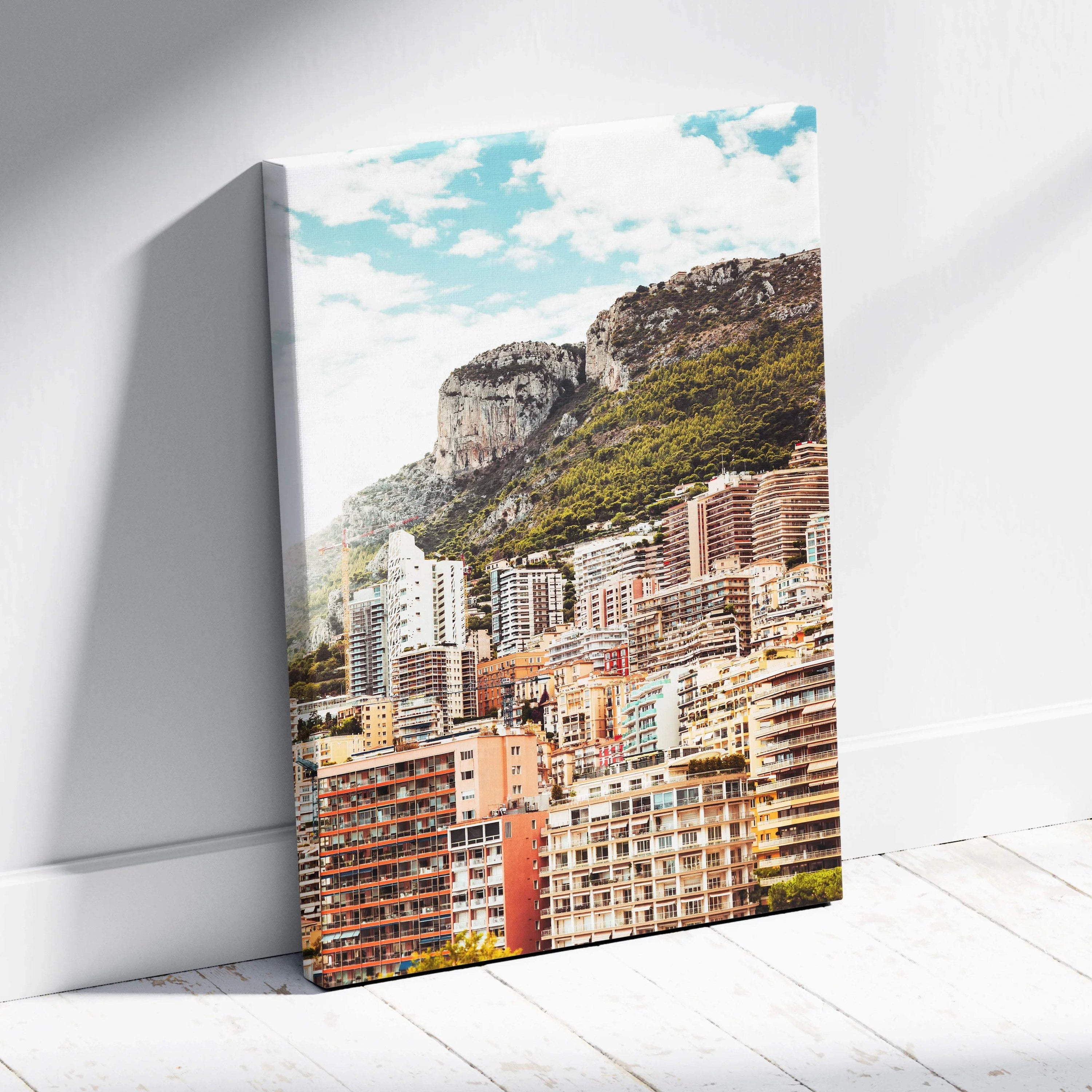 Canvas wall art featuring a colorful cityscape with high-rise buildings and a rocky mountain under a bright blue sky.