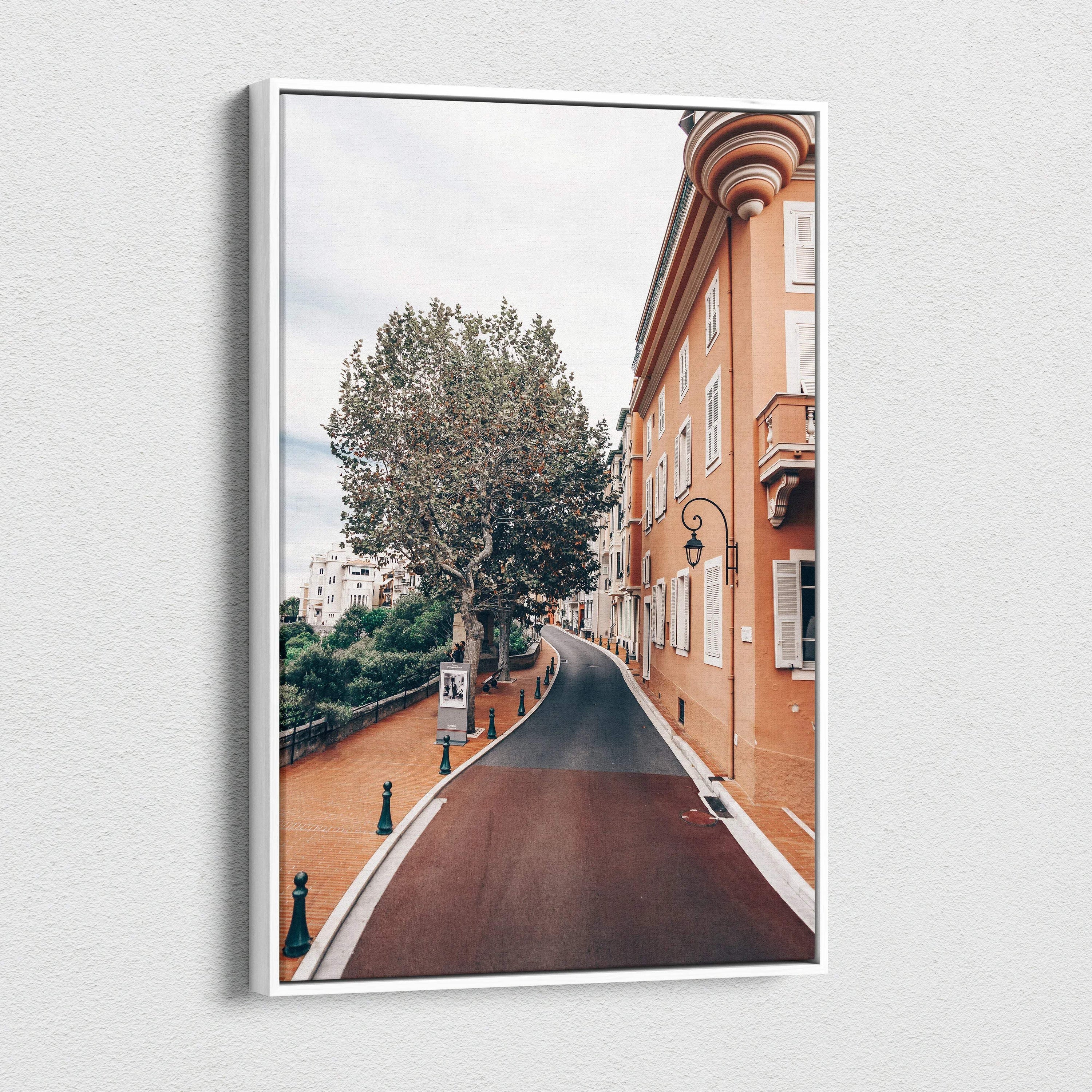 Canvas wall art featuring a curved street lined with a tall tree and historic orange-toned buildings under a cloudy sky.