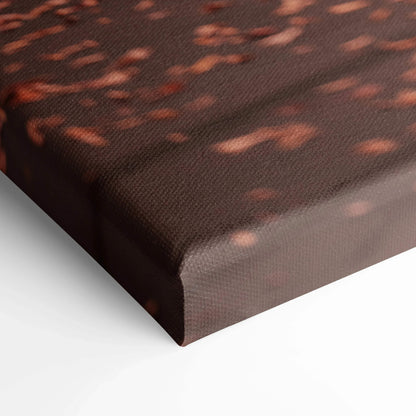 Close-up of textured brown canvas with abstract red and orange speckled pattern, wall art detail.