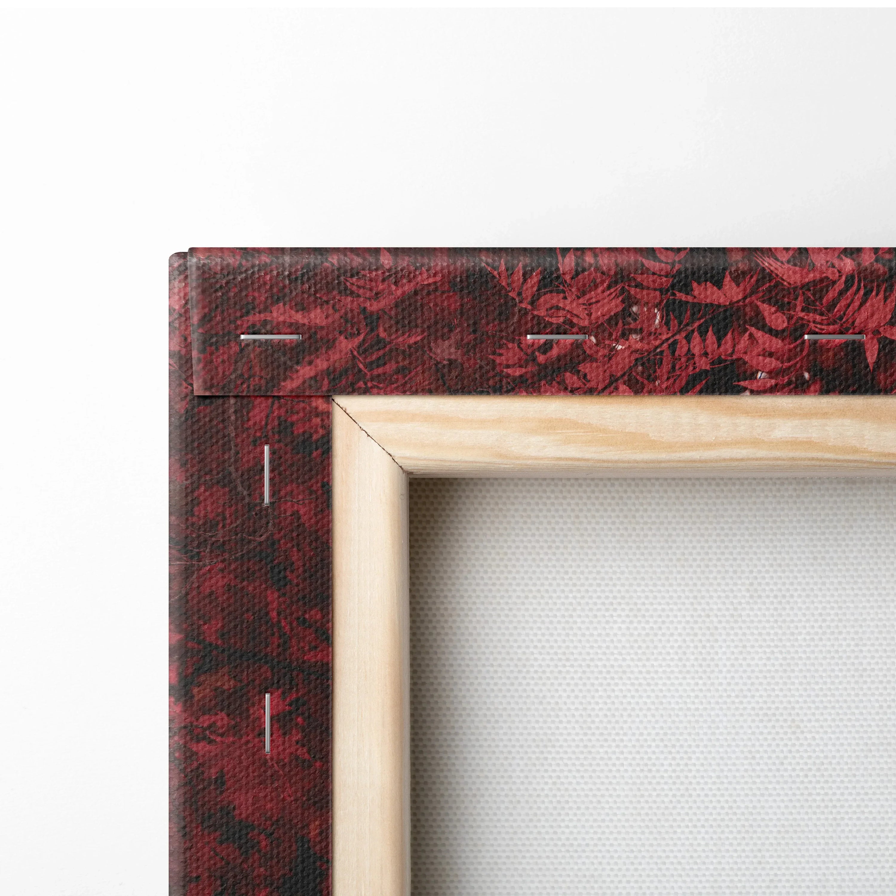 Close-up of wooden framed canvas art with red floral patterned edge and white stretched fabric back for wall art display.