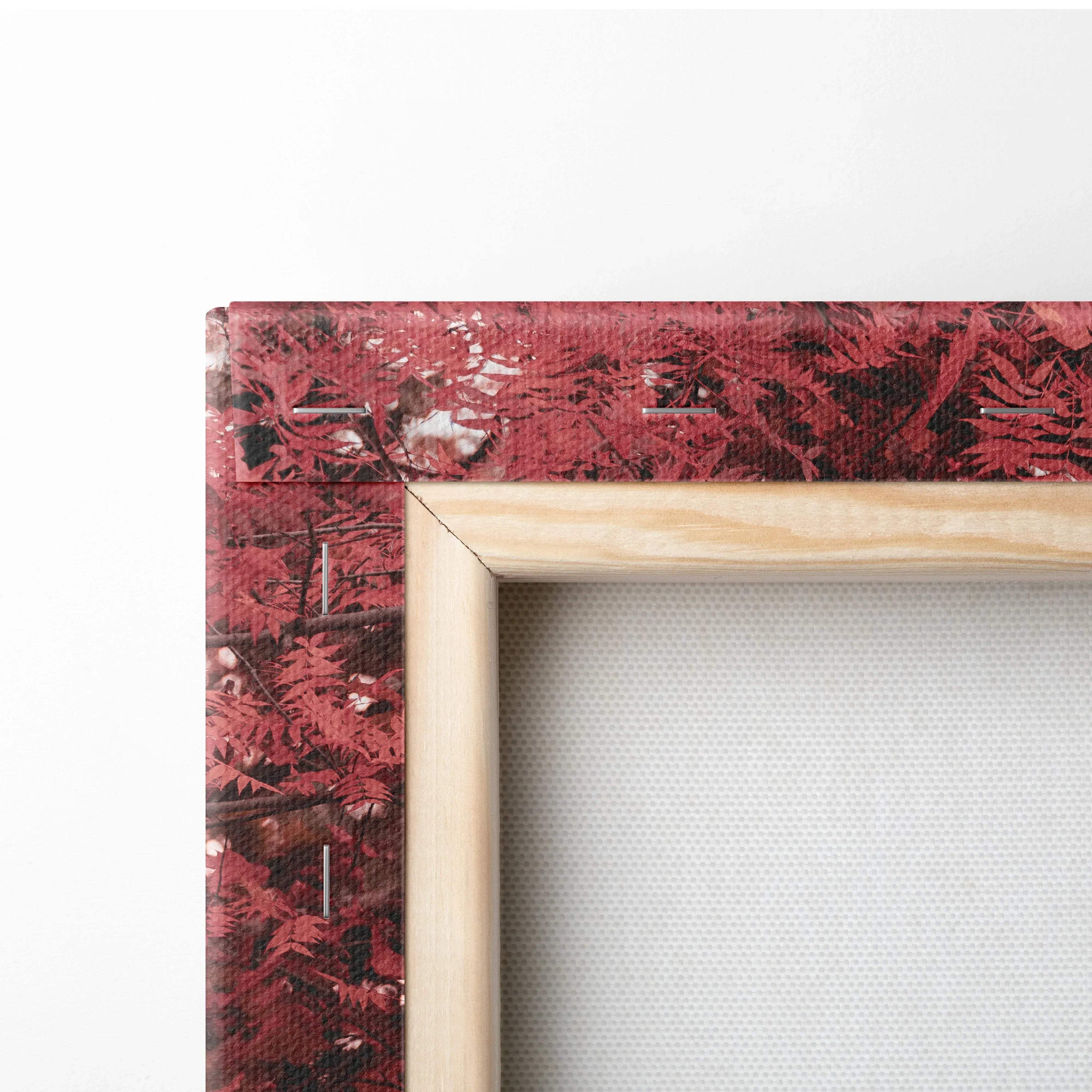 Close-up of red patterned canvas art corner with wooden frame, showcasing texture and detail.