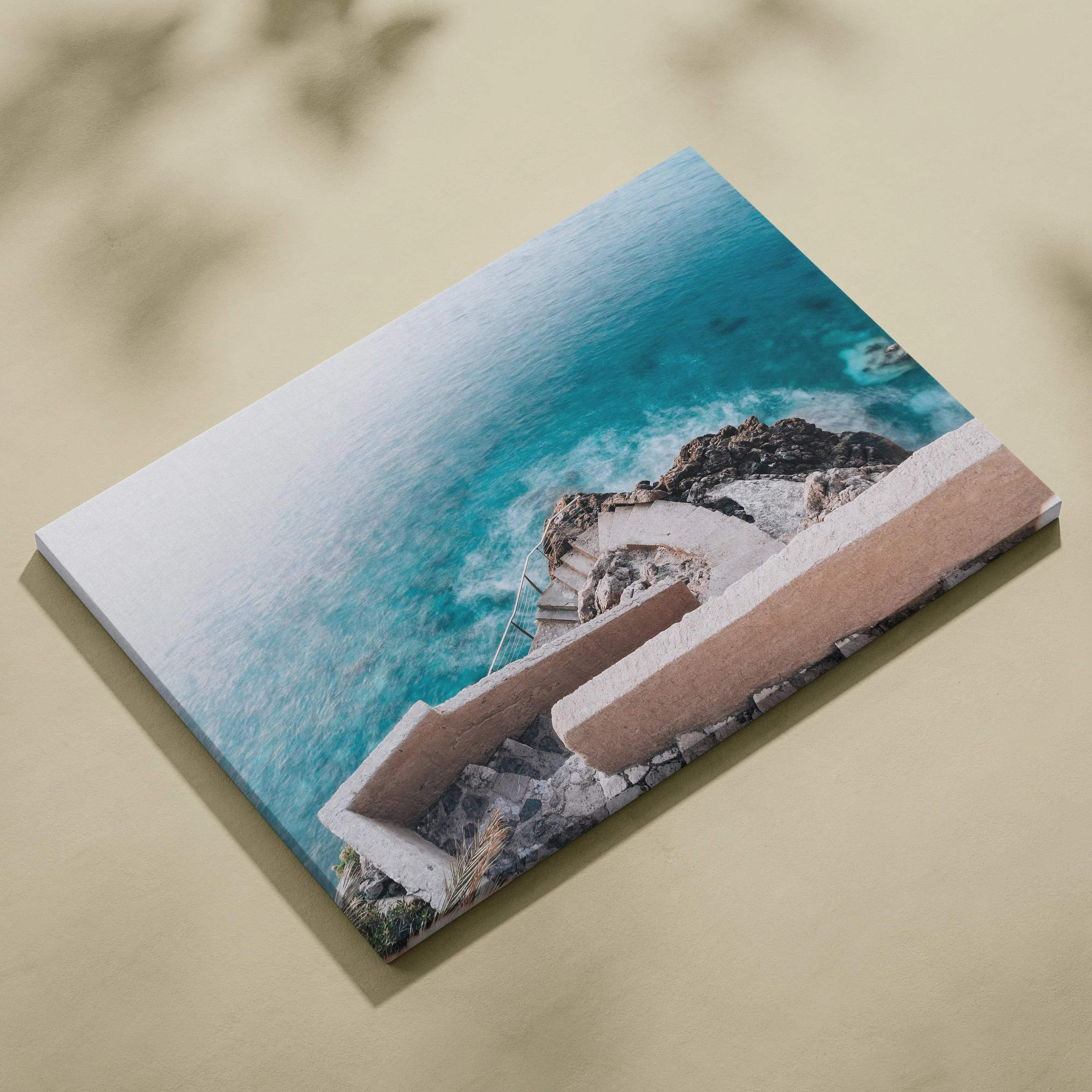 Rectangular canvas wall art featuring aerial view of beige architectural stairs descending toward turquoise ocean waves.