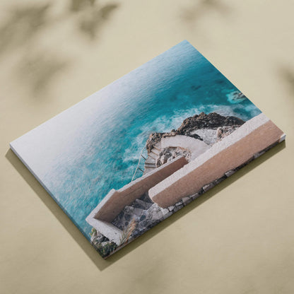 Rectangular canvas wall art featuring aerial view of beige architectural stairs descending toward turquoise ocean waves.