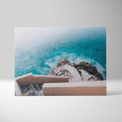 Canvas wall art showing curved beige architectural stairs descending toward turquoise ocean waves.