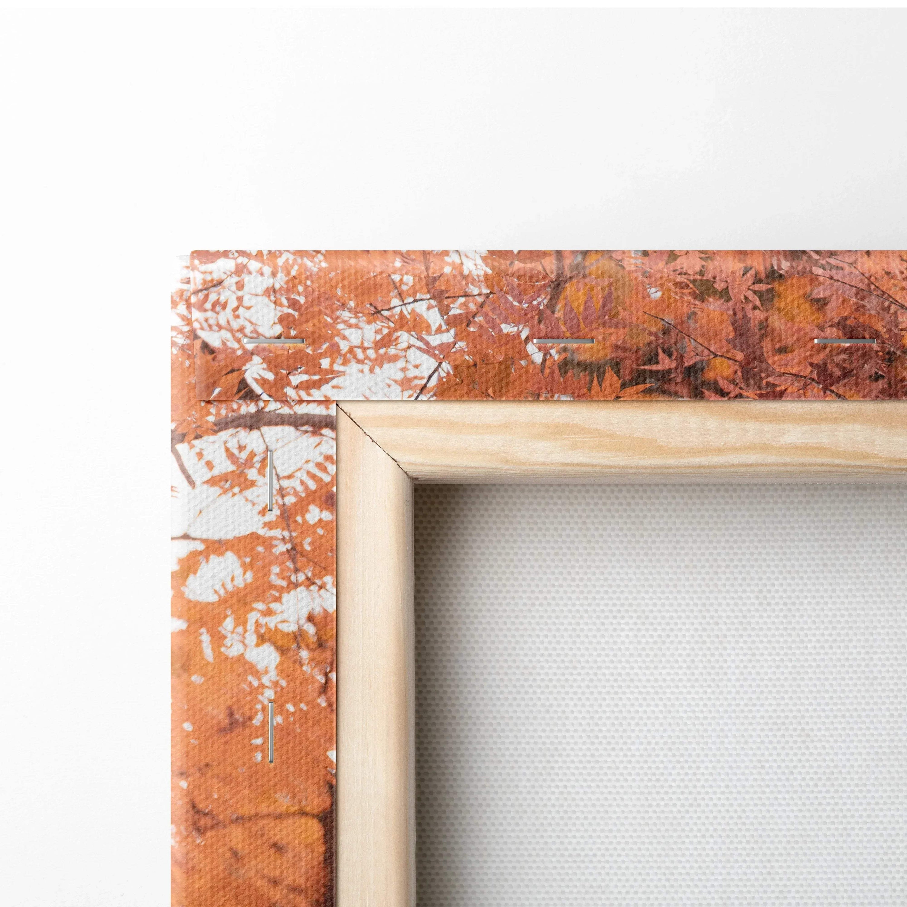 Close-up of vertical canvas art with orange and white abstract design and natural wood frame edge.