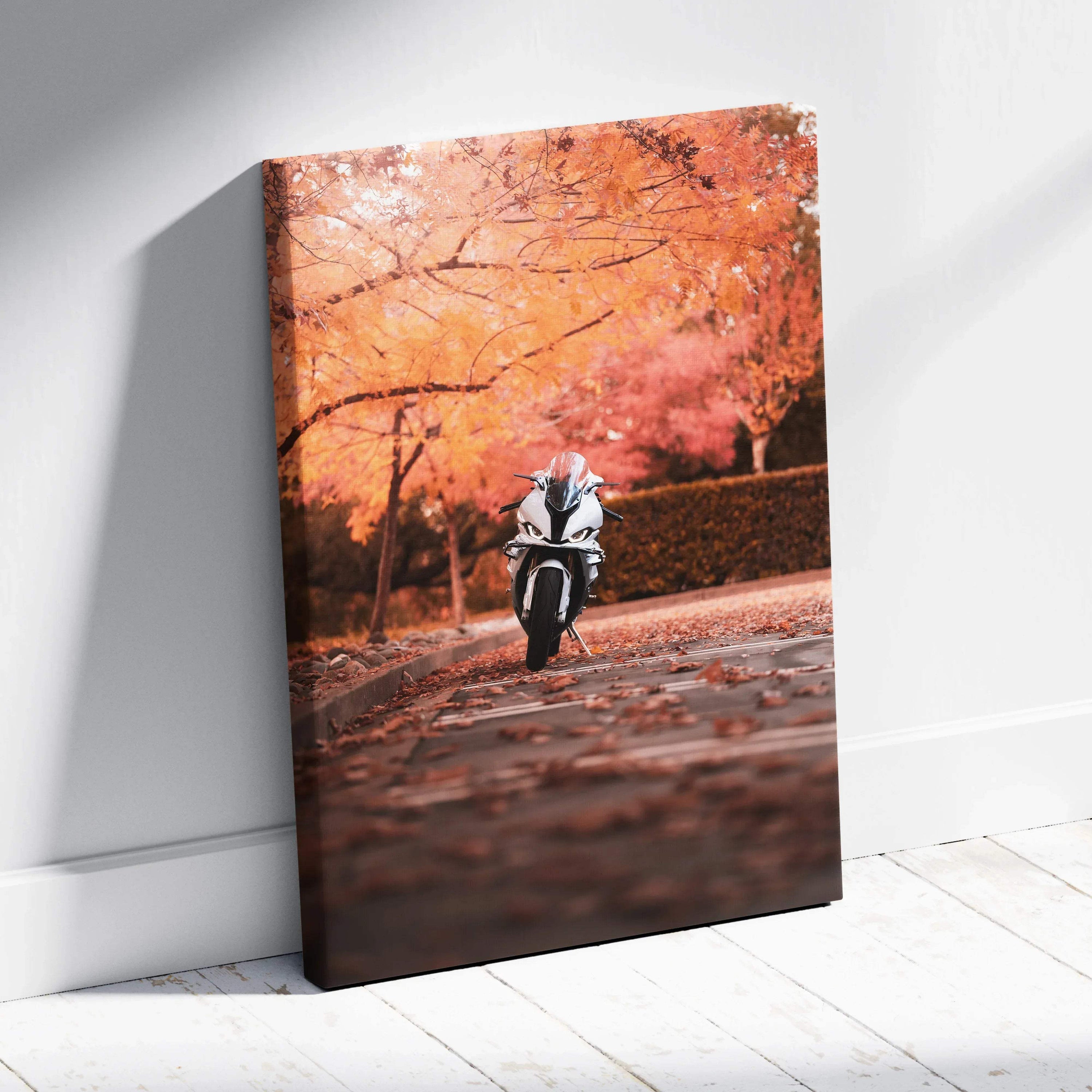 Vertical canvas art of a white BMW S1000RR motorcycle riding on a leaf-covered road with orange autumn trees background.