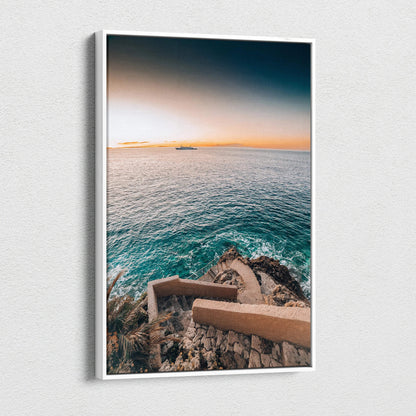 Canvas wall art featuring a serene ocean view with rocky coastline and stairs, warm sunset tones.