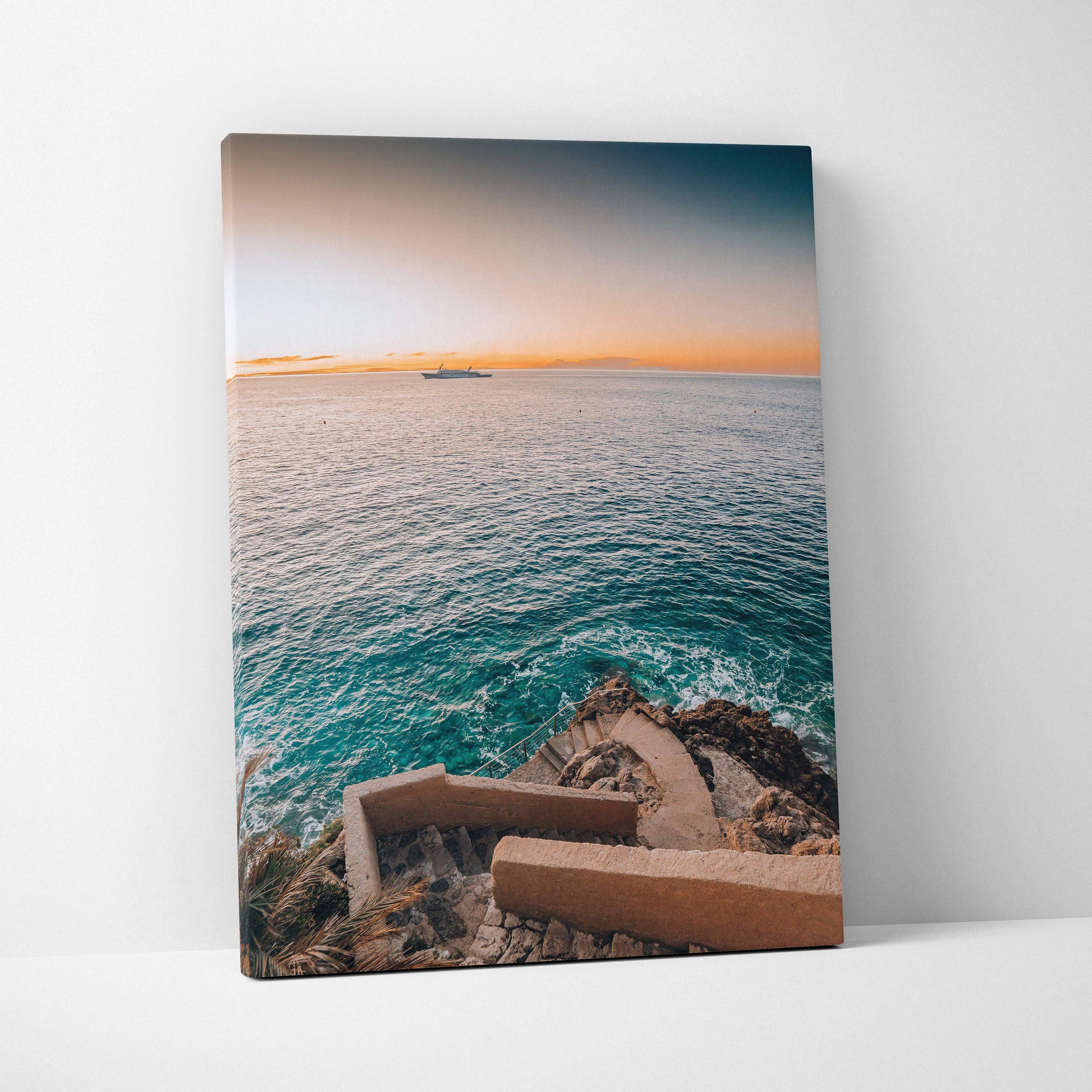 Canvas wall art featuring a coastal view with a stairway descending to turquoise ocean water under a soft orange and blue.