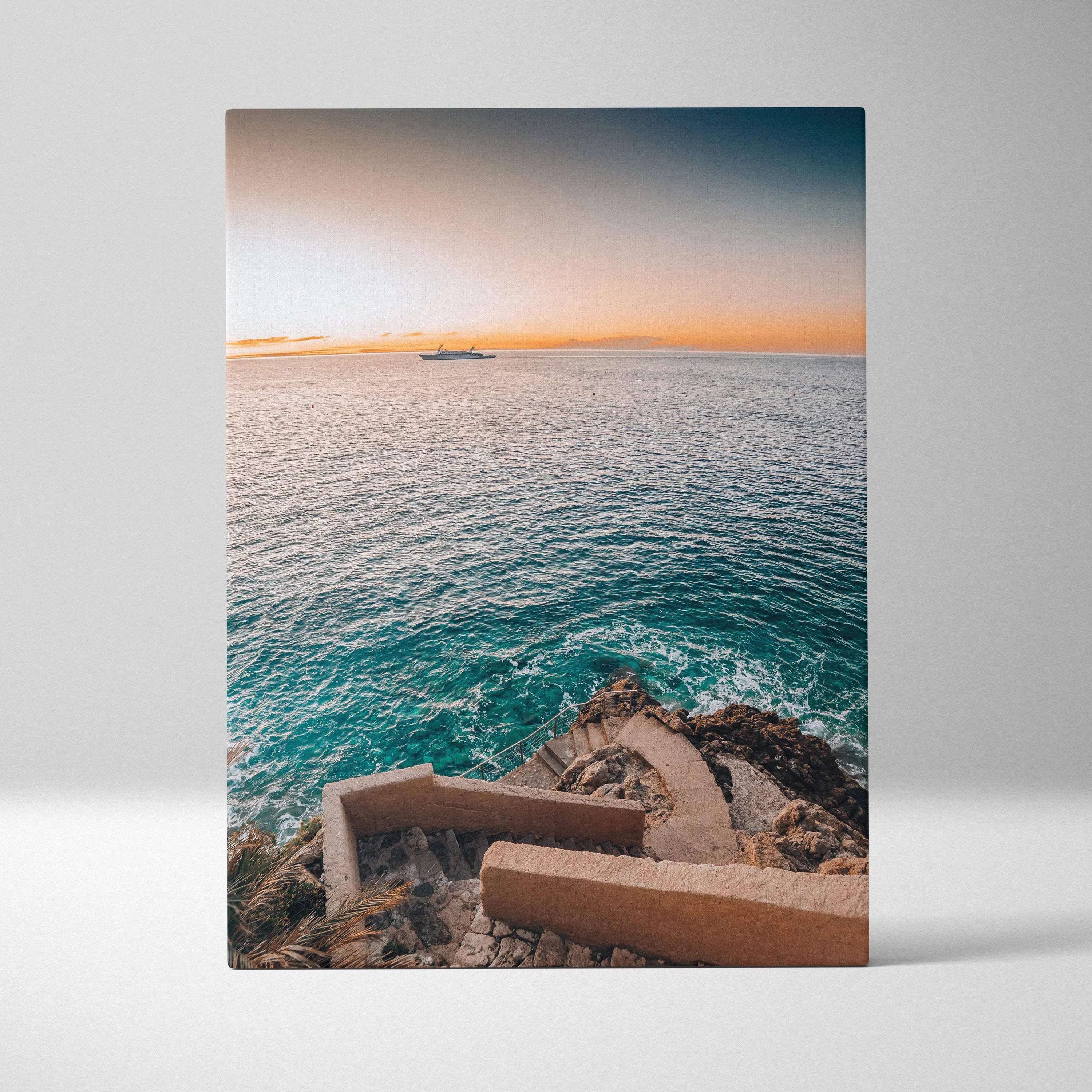 Vertical canvas art showing serene ocean waves at sunset with rocky shoreline and stone steps, elegant wall art.