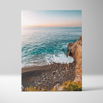 Canvas wall art depicting a serene beach scene with blue ocean waves, rocky shore, and soft pastel sky at sunset.