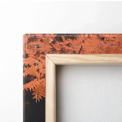Close-up of wooden-framed canvas wall art with orange fern leaves design on textured canvas.