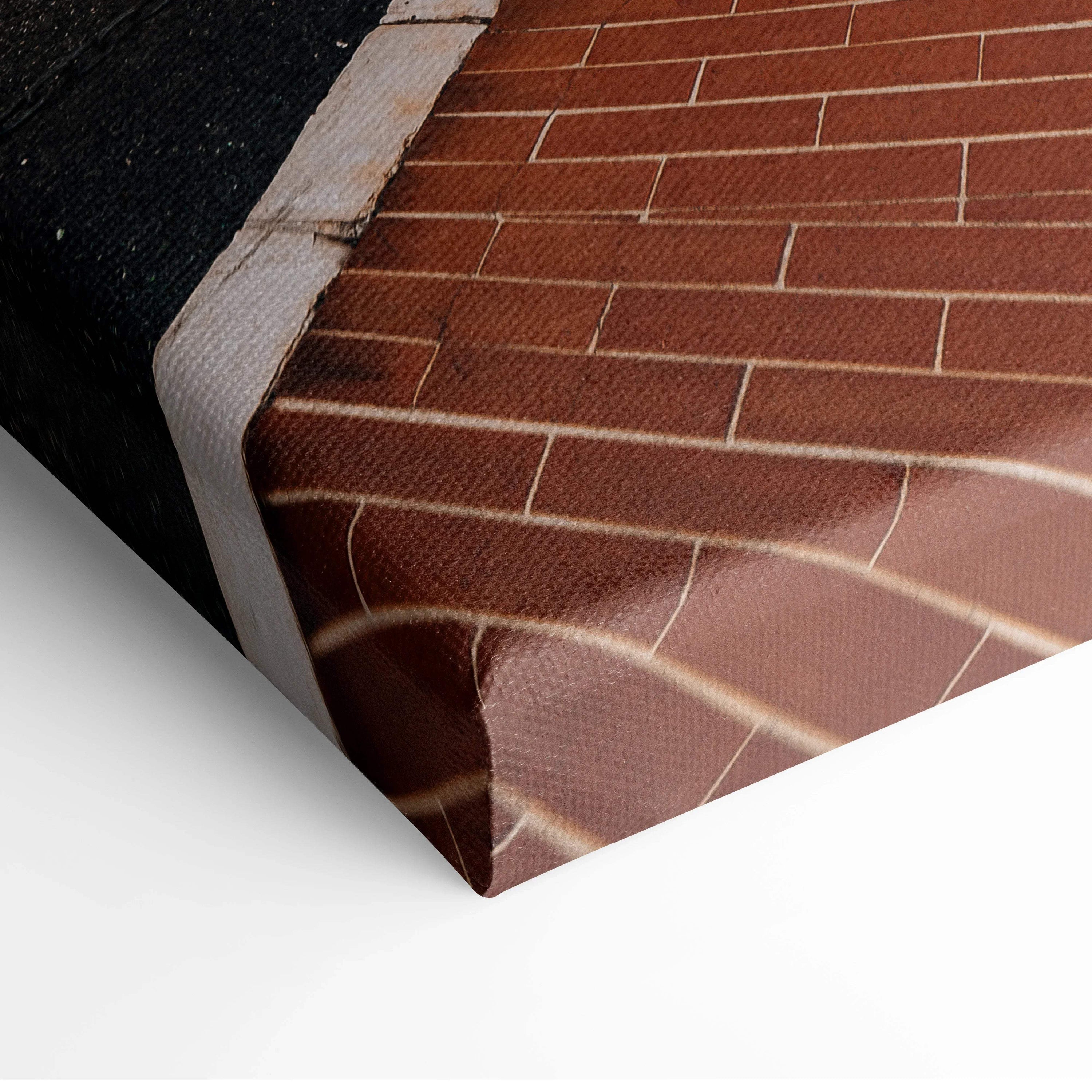 Close-up of textured canvas print featuring brick wall and architectural details in warm brown tones, stretched on wooden.