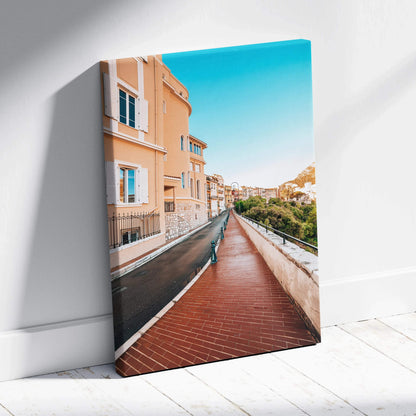Canvas wall art featuring a high-resolution digital print of pastel orange buildings along a red brick pathway under a.