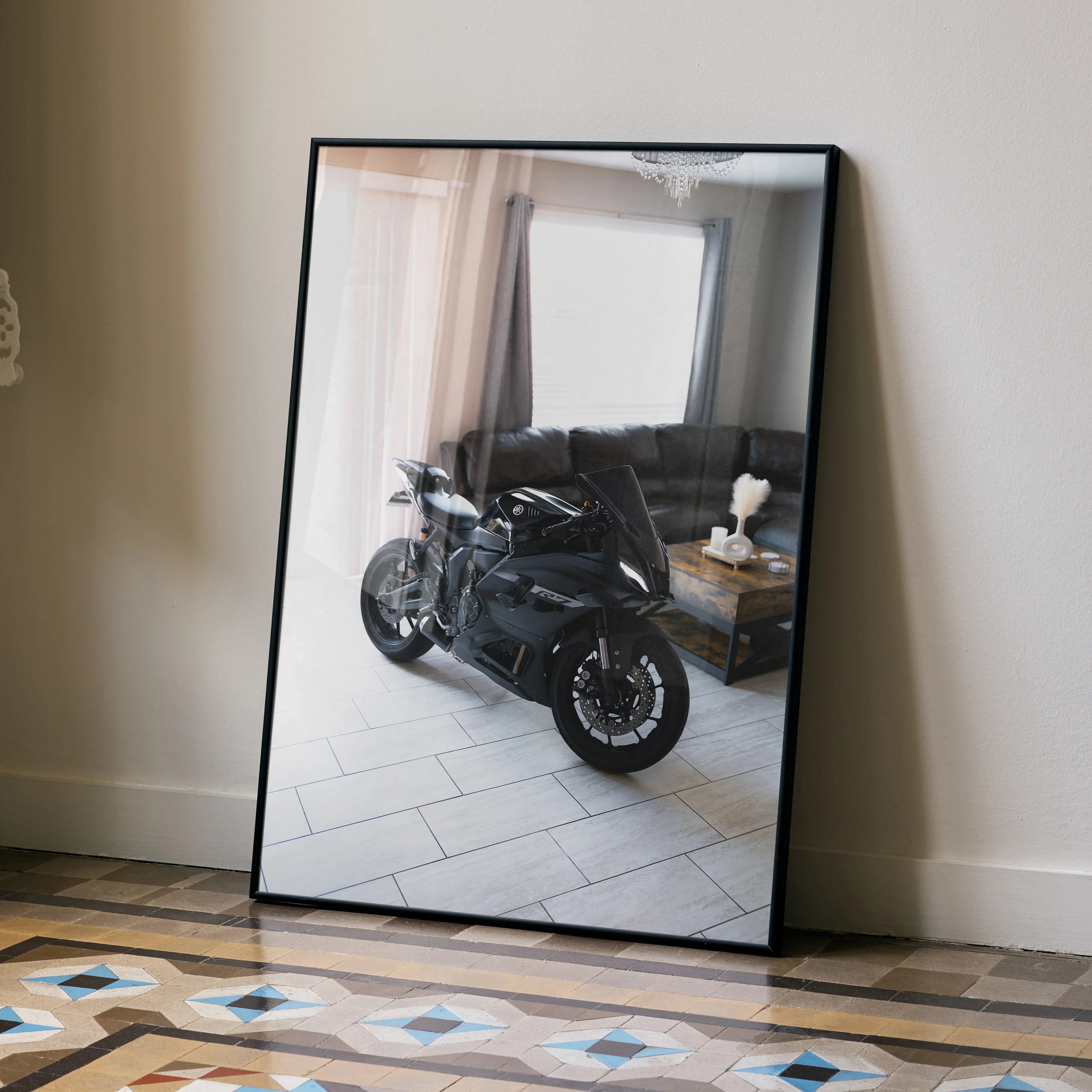 Yamaha R7 motorcycle poster in a black frame leaning against a beige wall, modern living room reflected on surface.