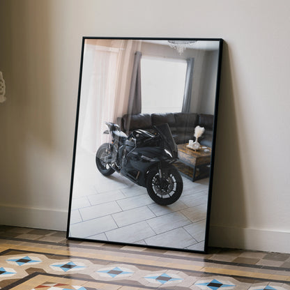 Yamaha R7 motorcycle poster in a black frame leaning against a beige wall, modern living room reflected on surface.