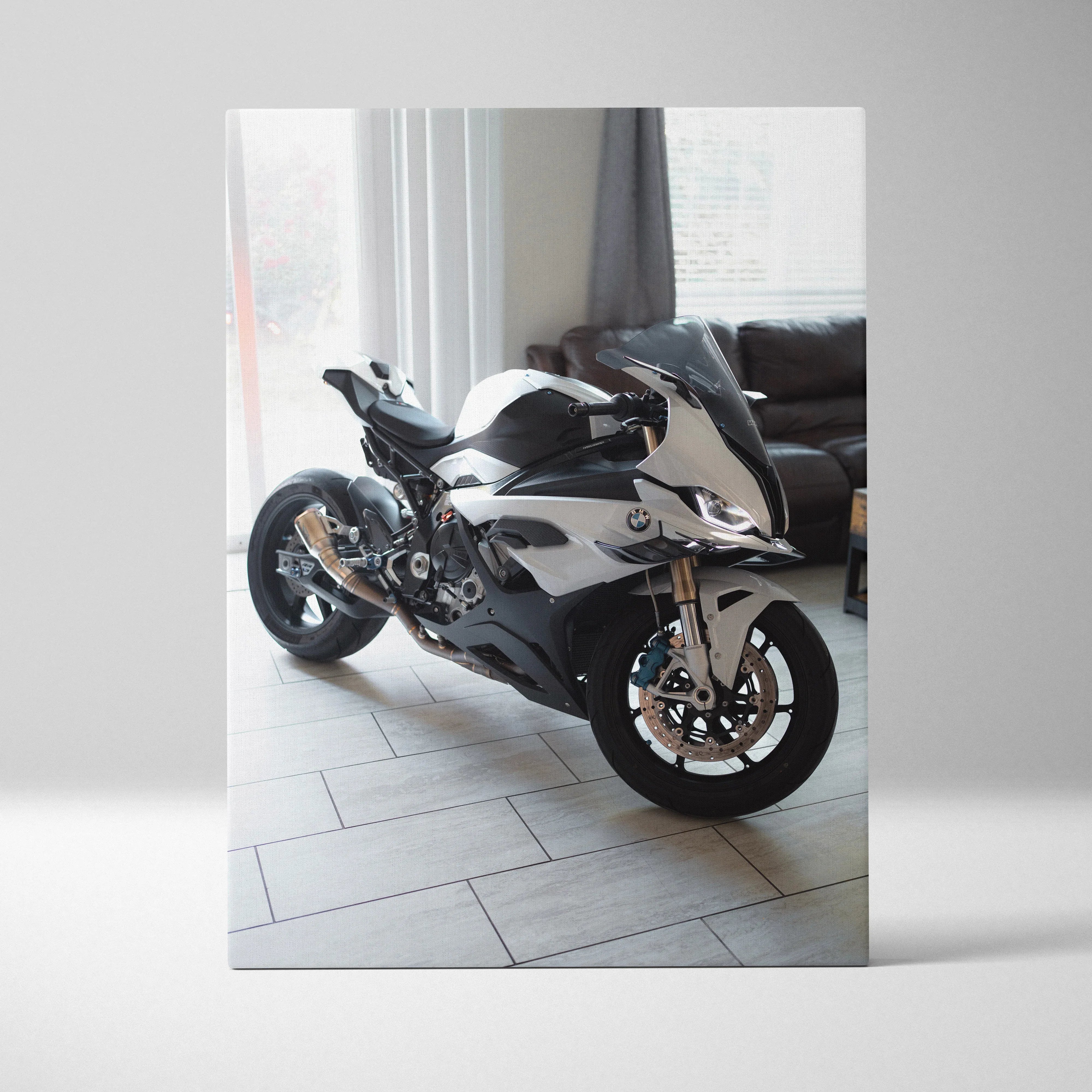 Black and white BMW S1000RR motorcycle canvas art hanging on wall above gray sofa in modern living room.