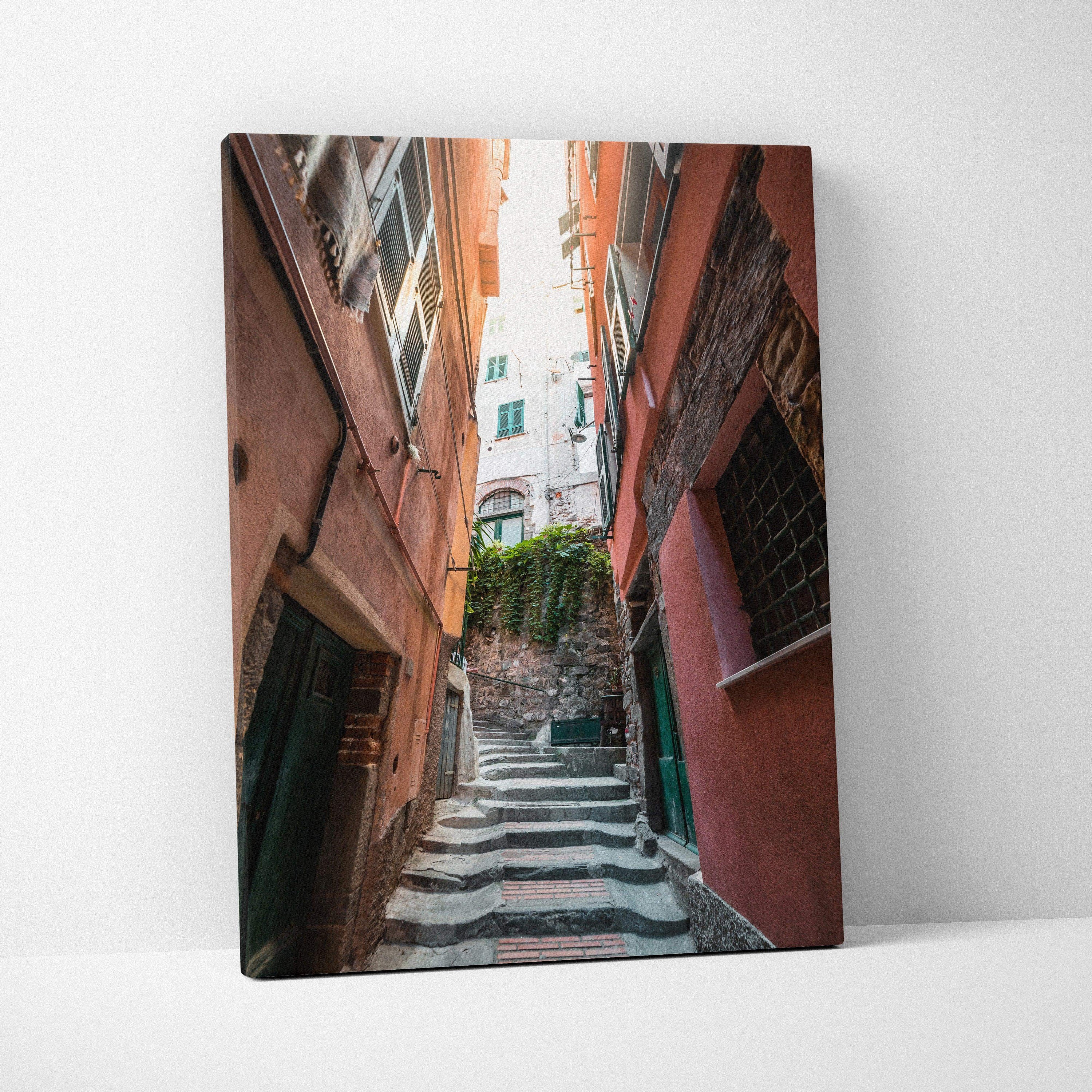 Canvas wall art featuring a narrow, sunlit alley between tall, warm-toned buildings with stairs leading upward.