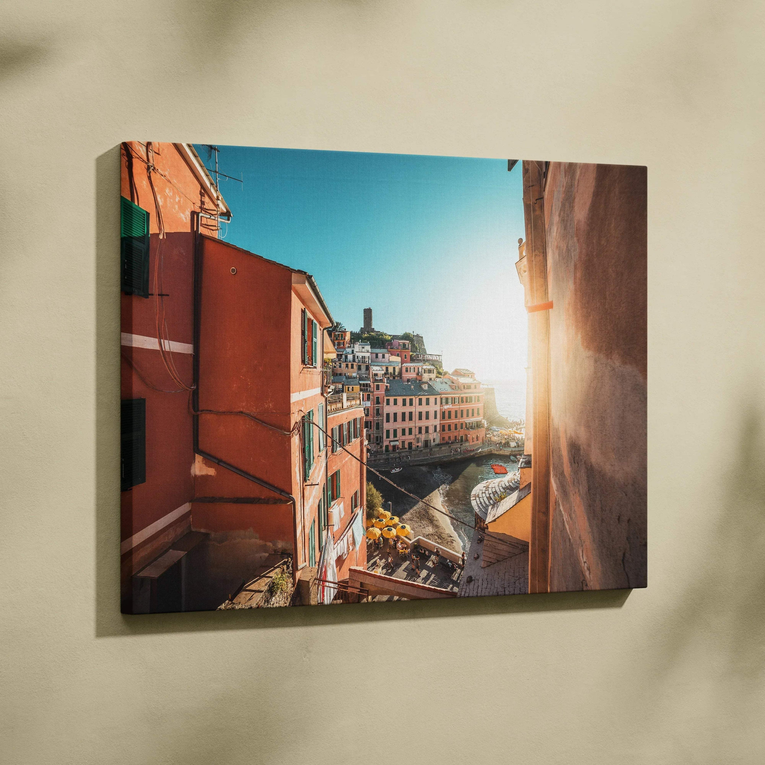 Canvas wall art featuring vibrant Mediterranean buildings with warm tones and sunlight over a coastal village.