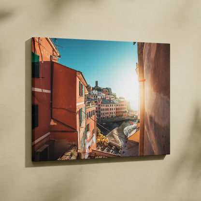 Canvas wall art featuring vibrant Mediterranean buildings with warm tones and sunlight over a coastal village.