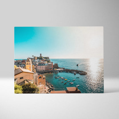Canvas wall art of coastal architecture with buildings and boats on a sunlit ocean bay.