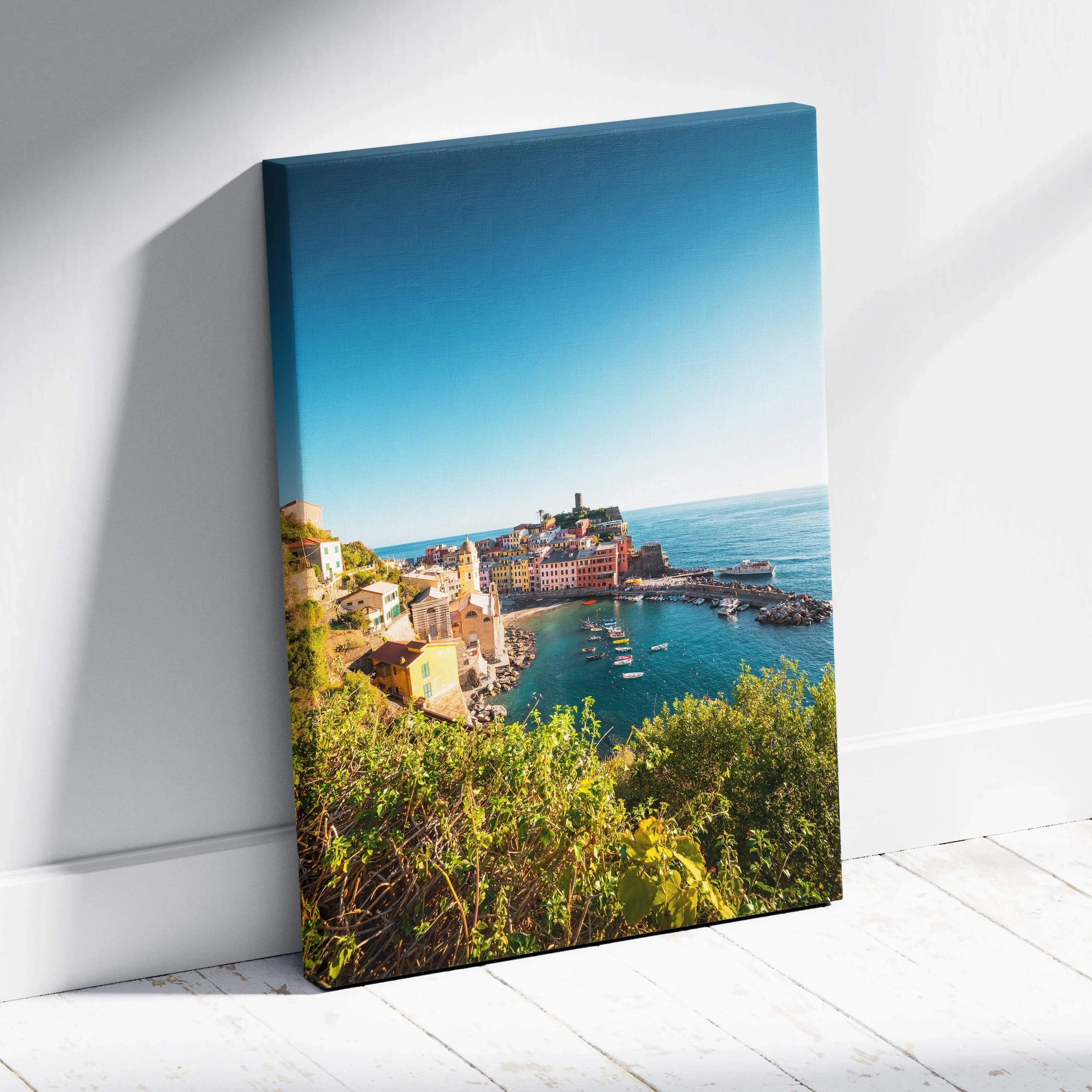 Vertical canvas wall art featuring a vibrant coastal town with buildings and harbor under a clear blue sky.