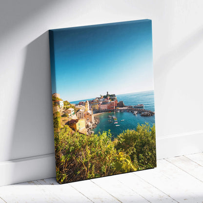 Vertical canvas wall art featuring a vibrant coastal town with buildings and harbor under a clear blue sky.