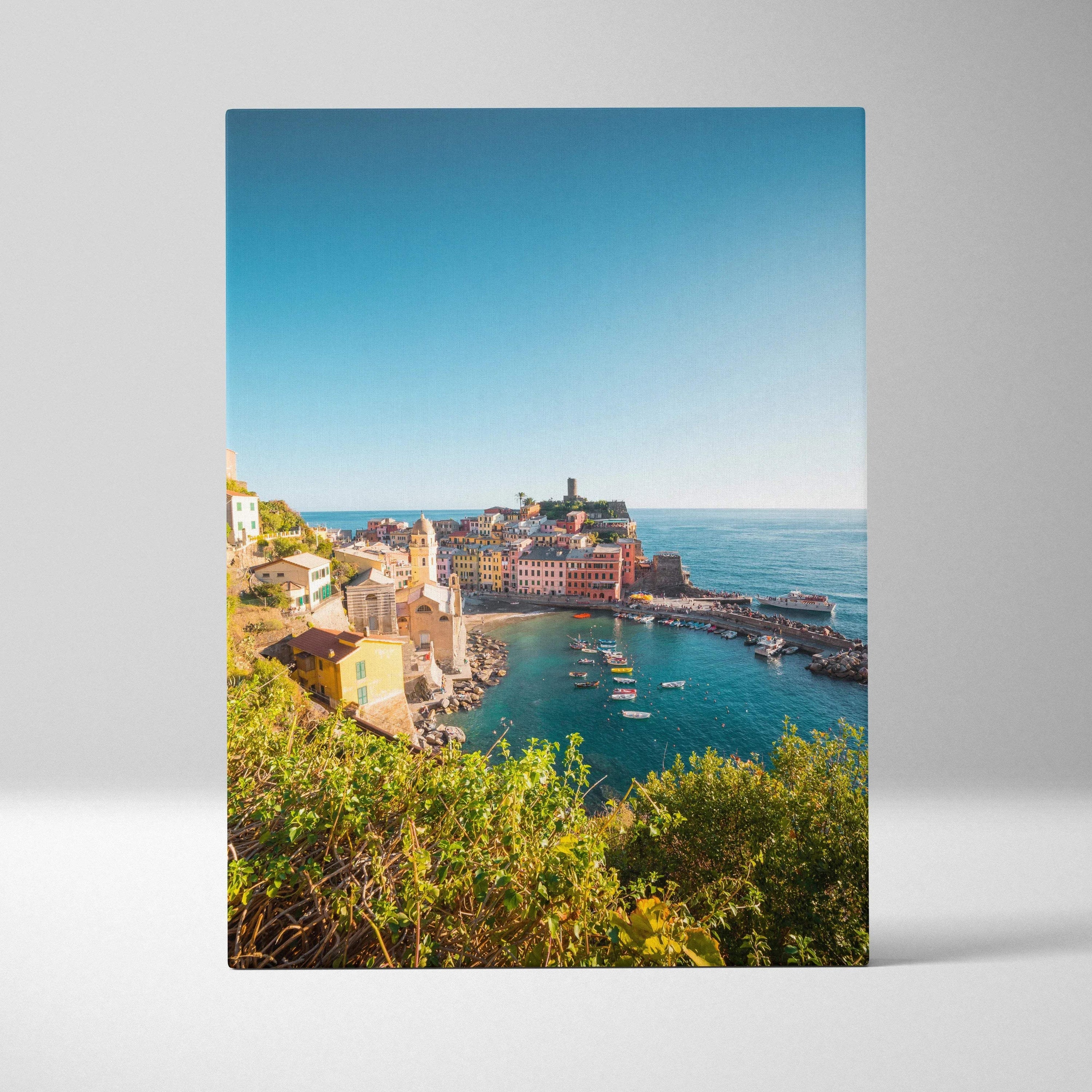 Vertical canvas wall art showcasing colorful coastal buildings and clear blue sea under a bright sky.