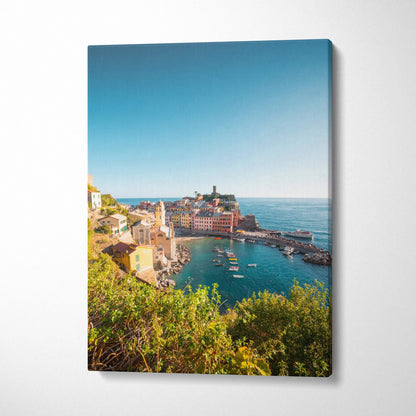 Vertical canvas wall art featuring vibrant coastal village with colorful buildings and boats under clear blue sky.