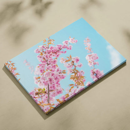Floral canvas wall art with vibrant pink flowers against a bright blue sky background.