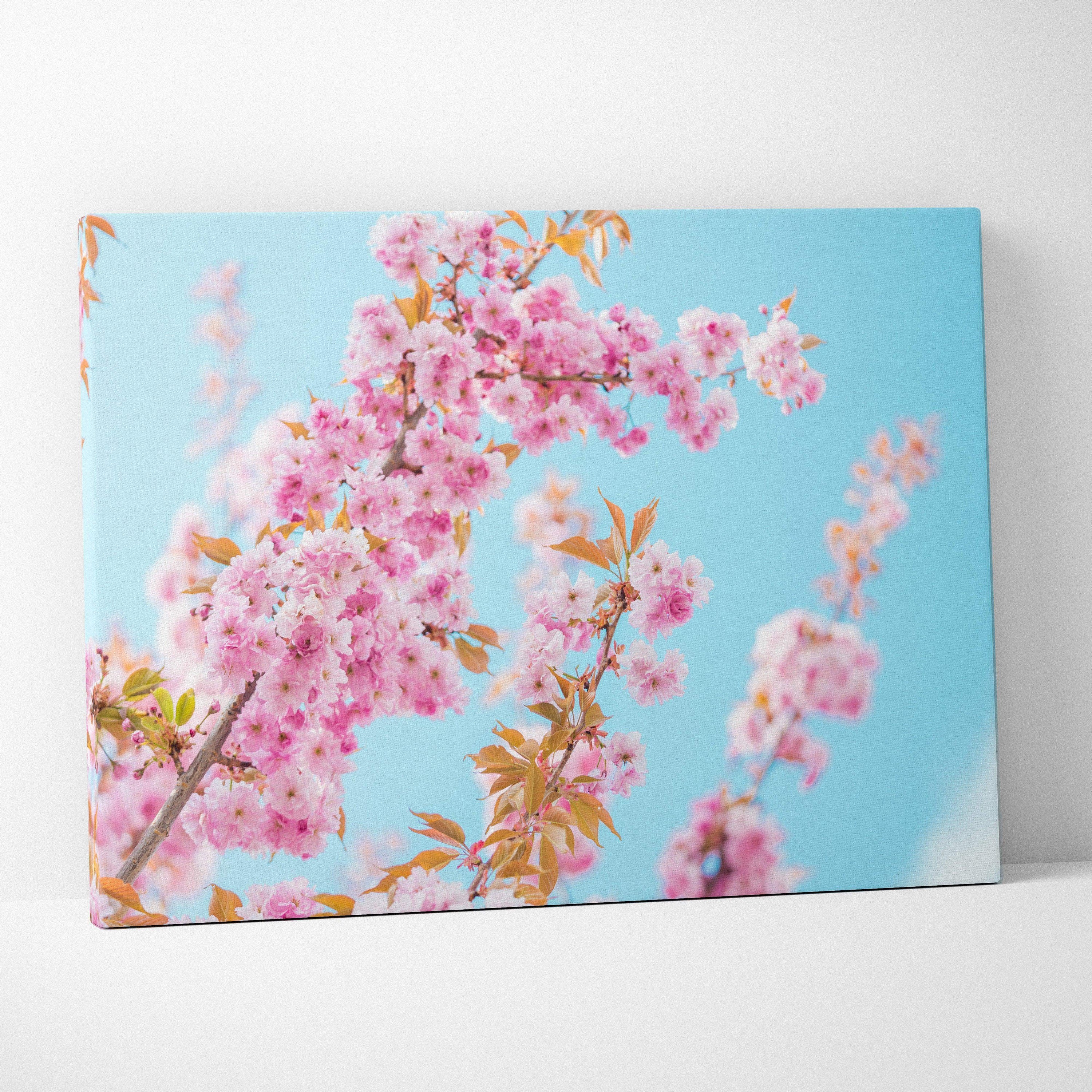 Vibrant pink flowers on canvas wall art with bright blue sky background, elegant decor.