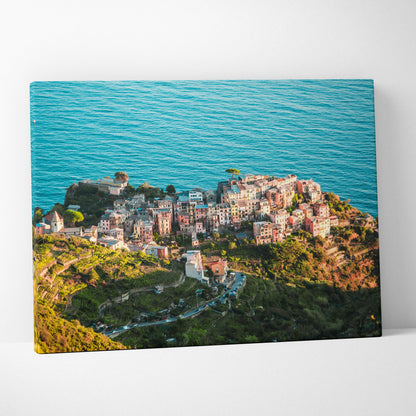 Canvas wall art featuring a colorful coastal village surrounded by vibrant blue ocean and green hills.