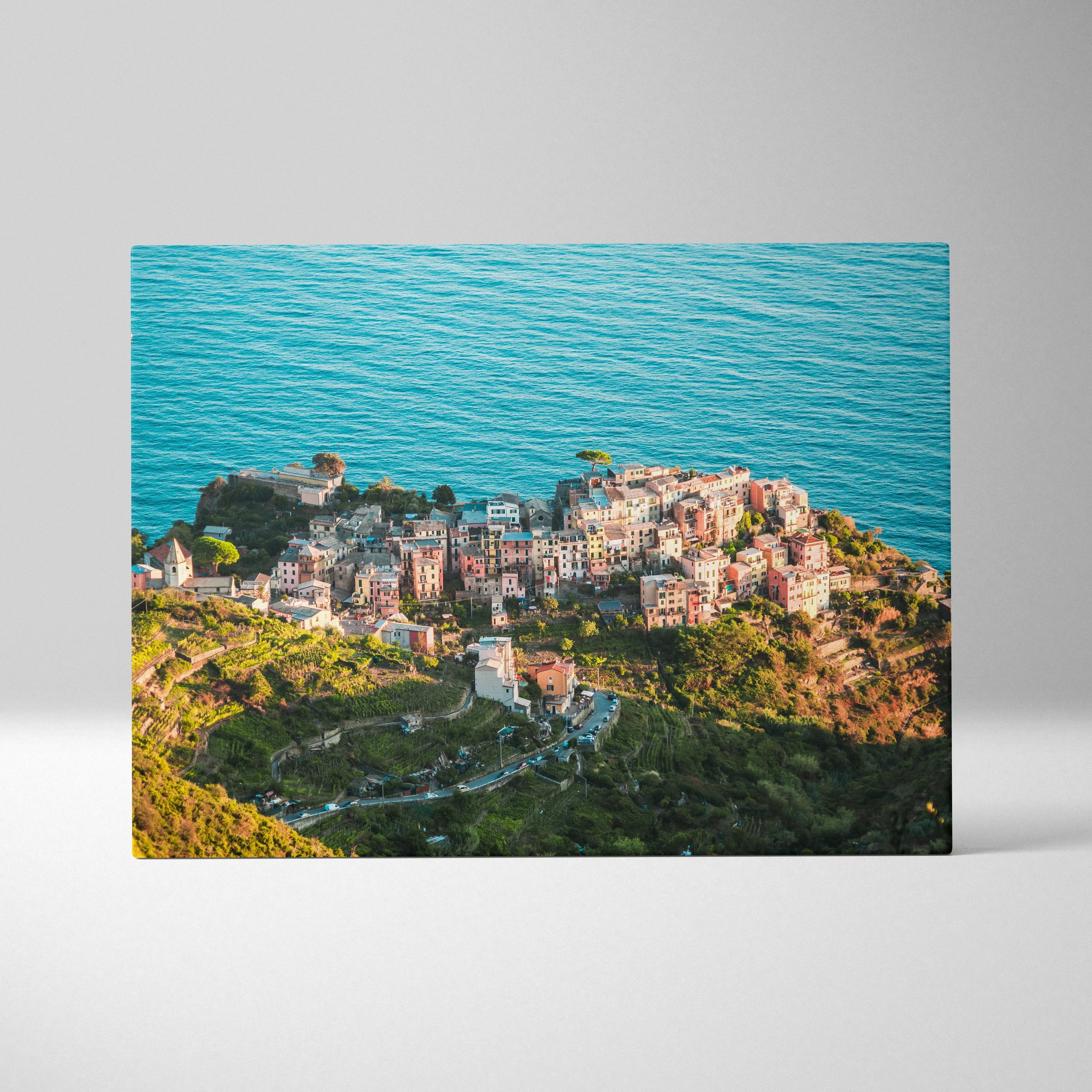 Canvas wall art featuring a coastal town with colorful buildings perched on cliffs above a vibrant blue ocean.