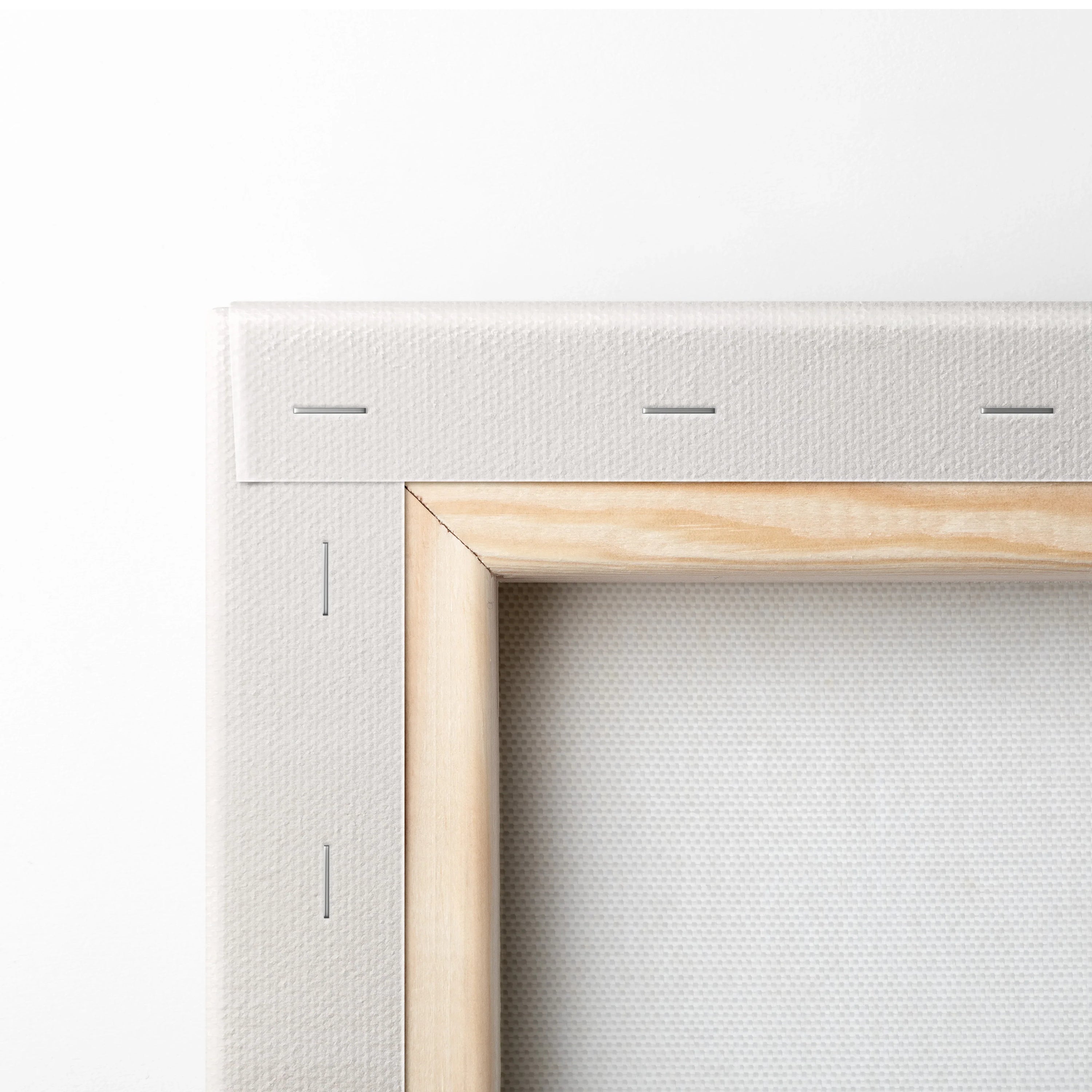 Close-up of blank white stretched canvas with wooden stretcher bars and stapled edges for wall art display.