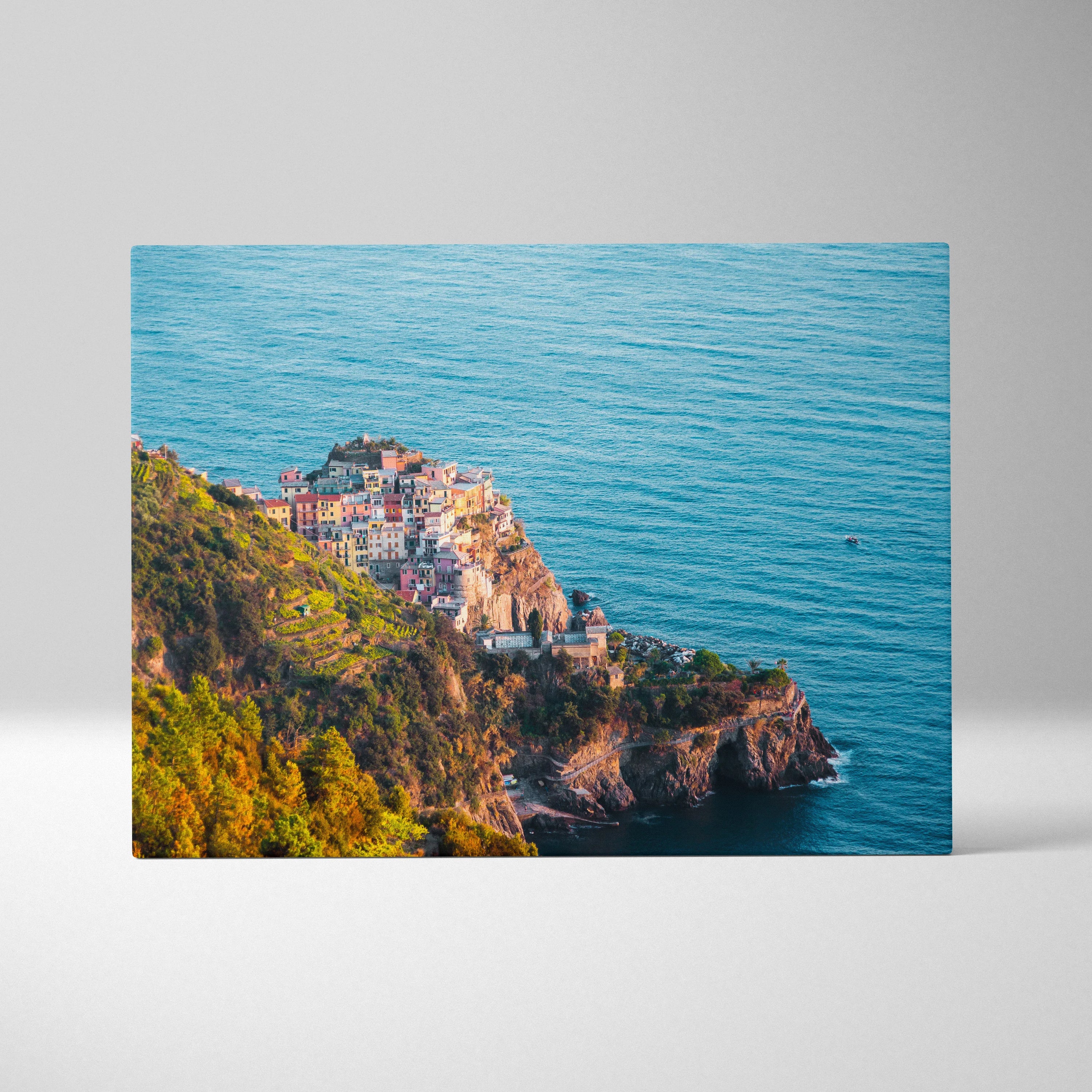 Canvas art featuring vibrant coastal buildings perched on rocky cliffs above a deep blue ocean, with lush greenery on the.