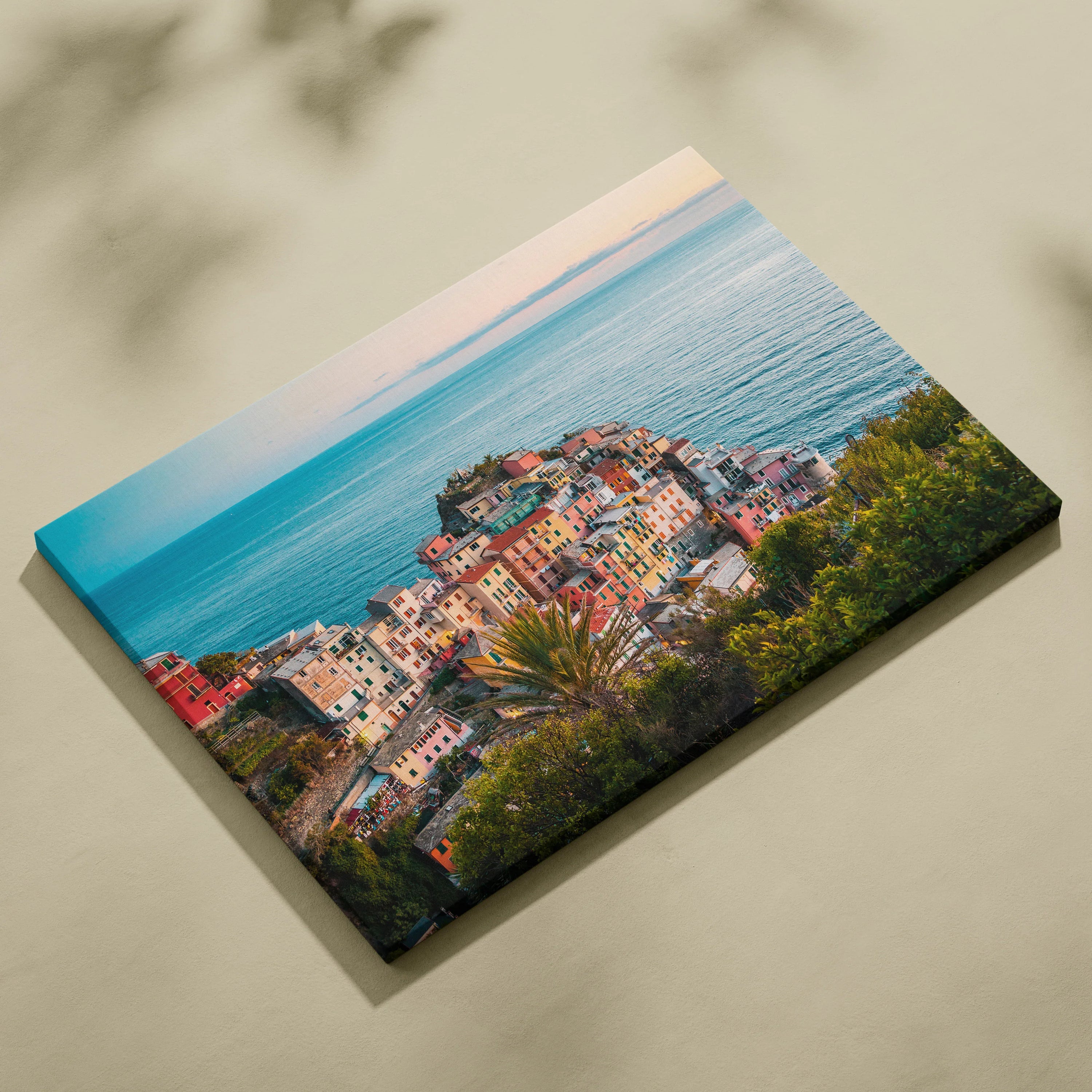 Colorful seaside townscape printed on rectangular canvas wall art with ocean backdrop and lush green foliage.