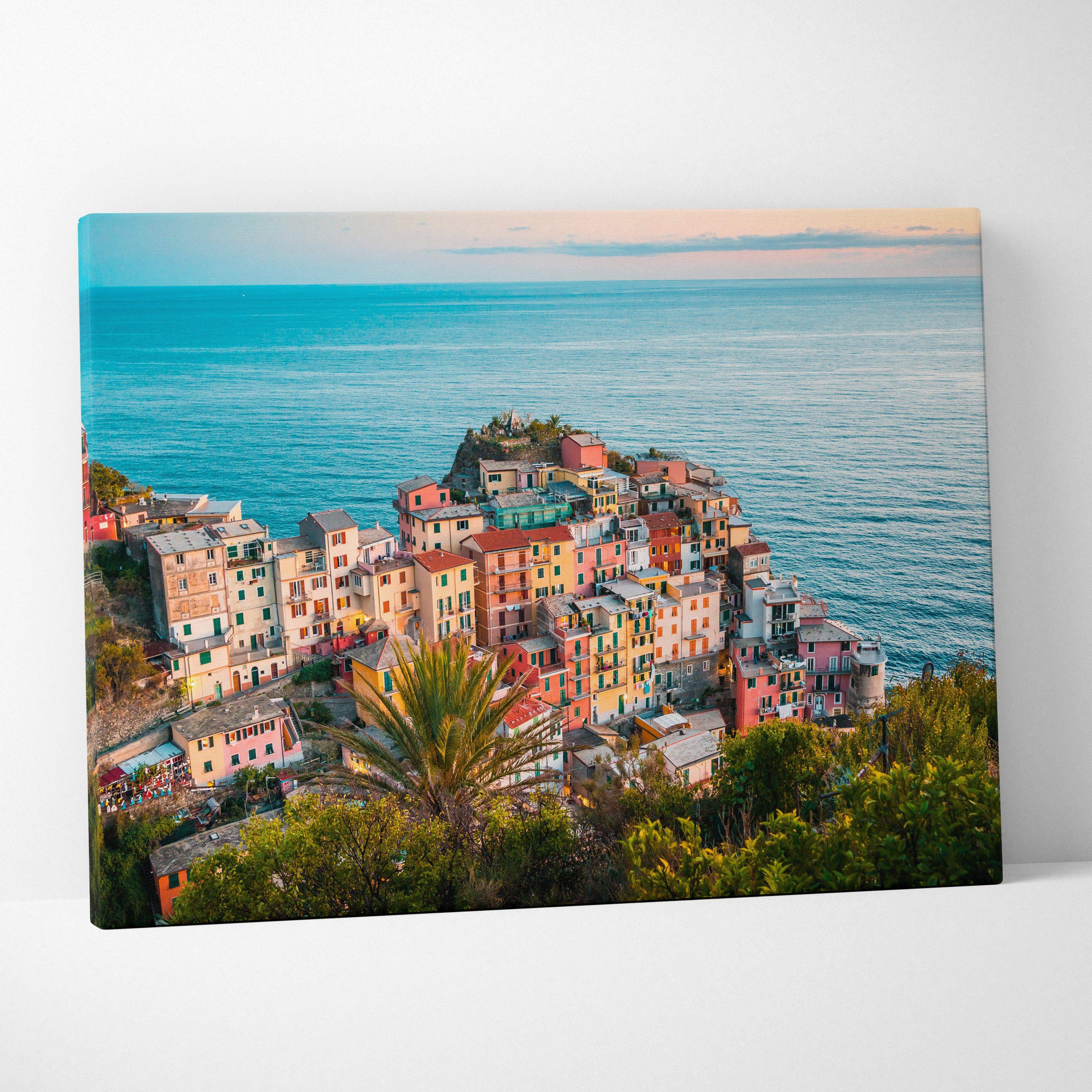 A vibrant colorful canvas print of a mediterranean coastal village with pastel buildings on cliffs by the sea