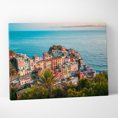Canvas wall art featuring colorful coastal buildings clustered on a cliff with calm ocean and pastel sky background.