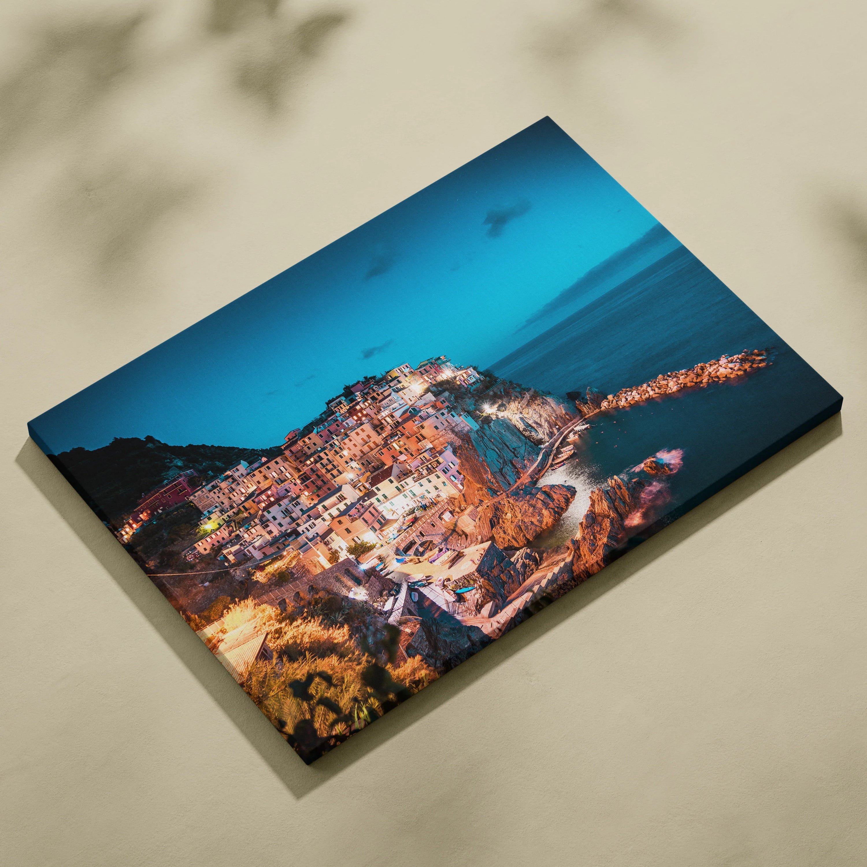 Canvas wall art featuring a vibrant nighttime coastal town with illuminated buildings against a deep blue ocean backdrop.